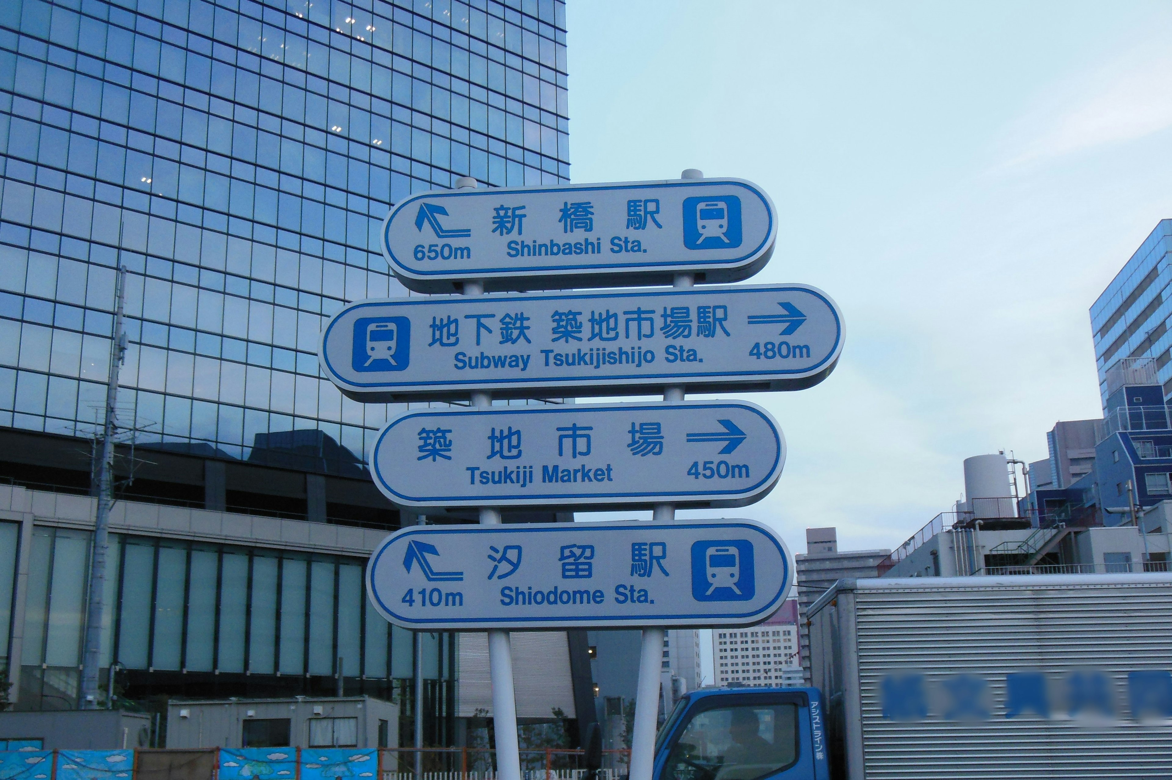 Blue directional signs in a city displaying station and street names