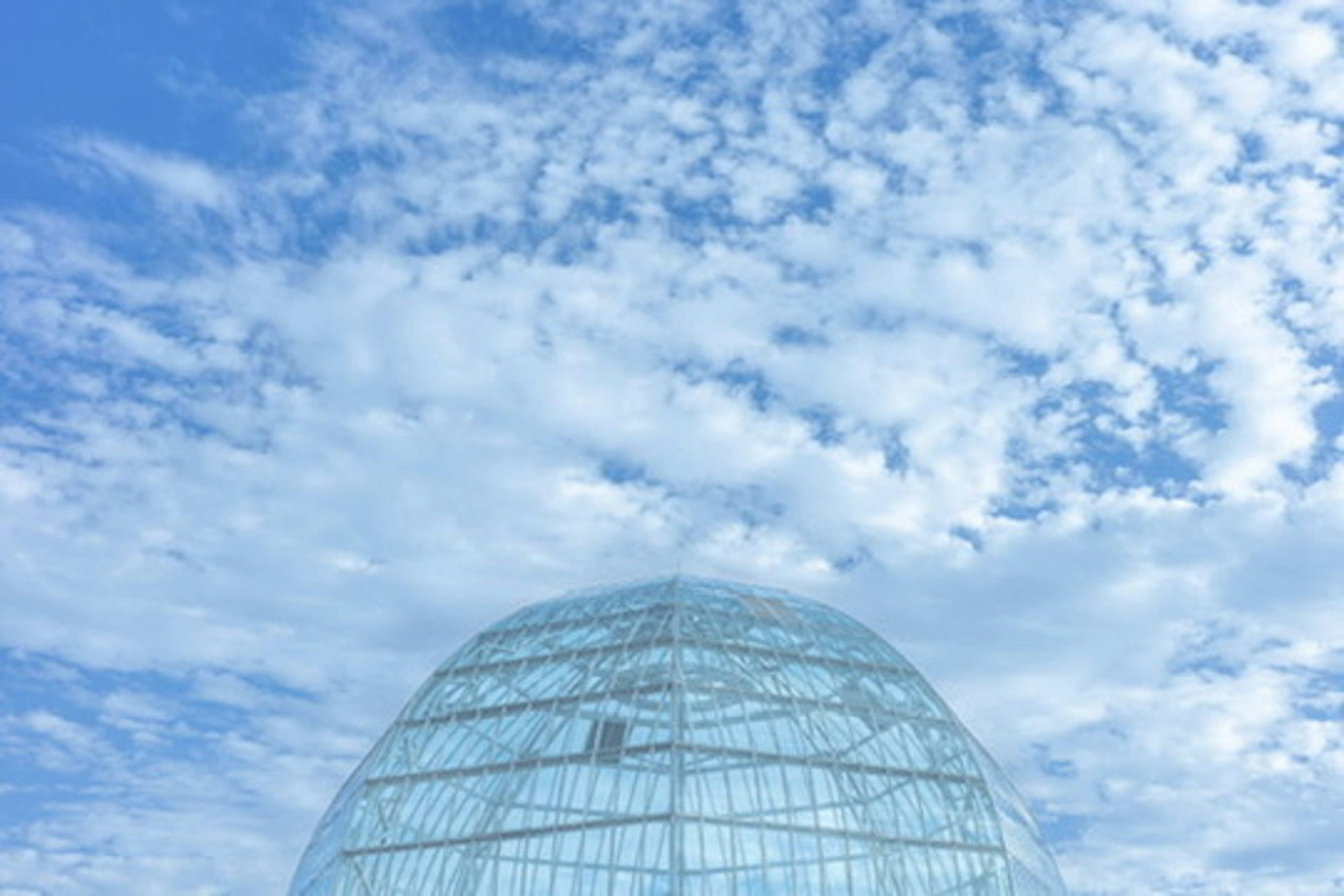 Glaskuppel vor dem Hintergrund eines blauen Himmels und weißer Wolken