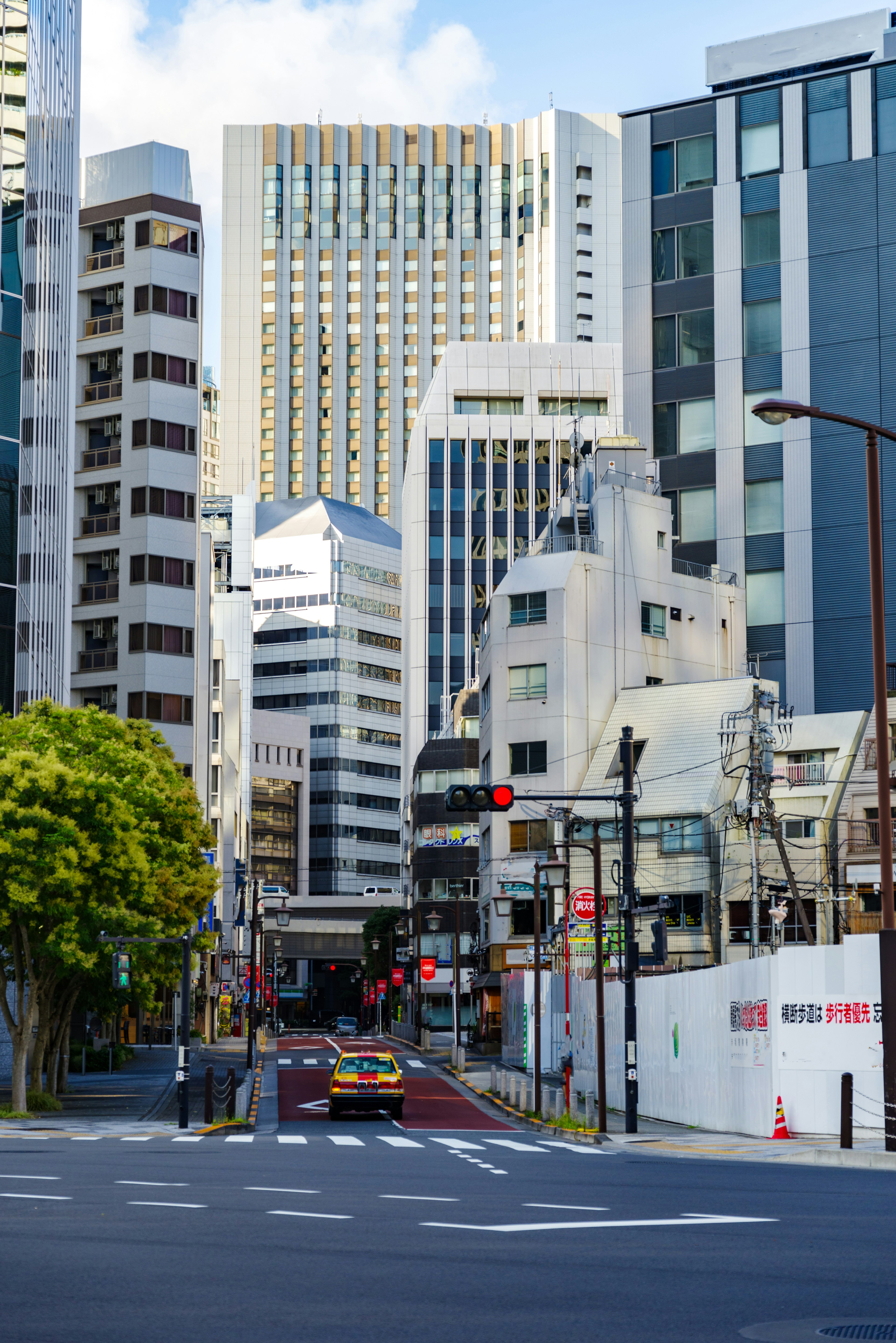 Urban landscape with tall buildings and clear blue sky featuring green trees