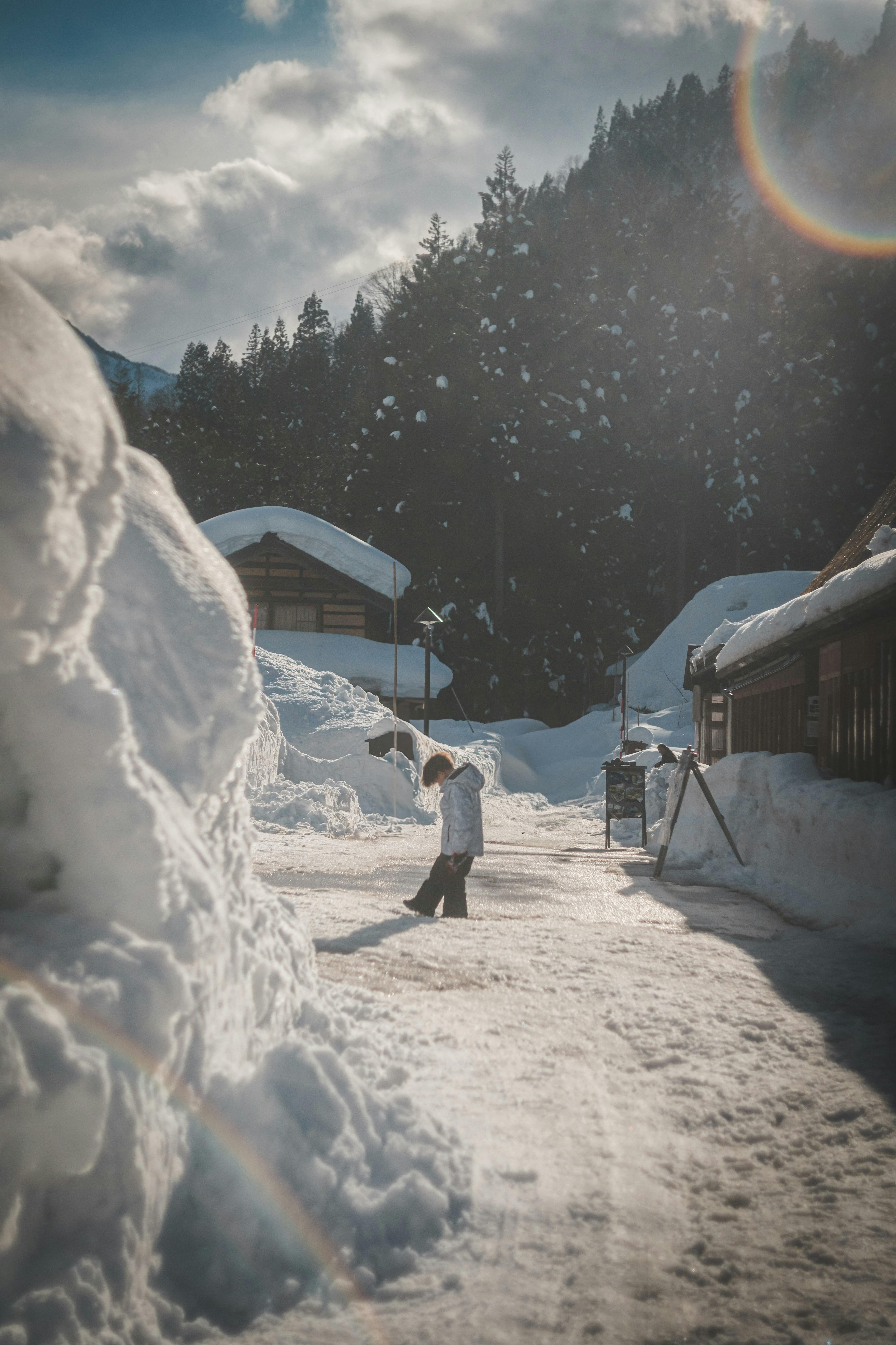 雪に覆われた道を歩く人と雪山の背景