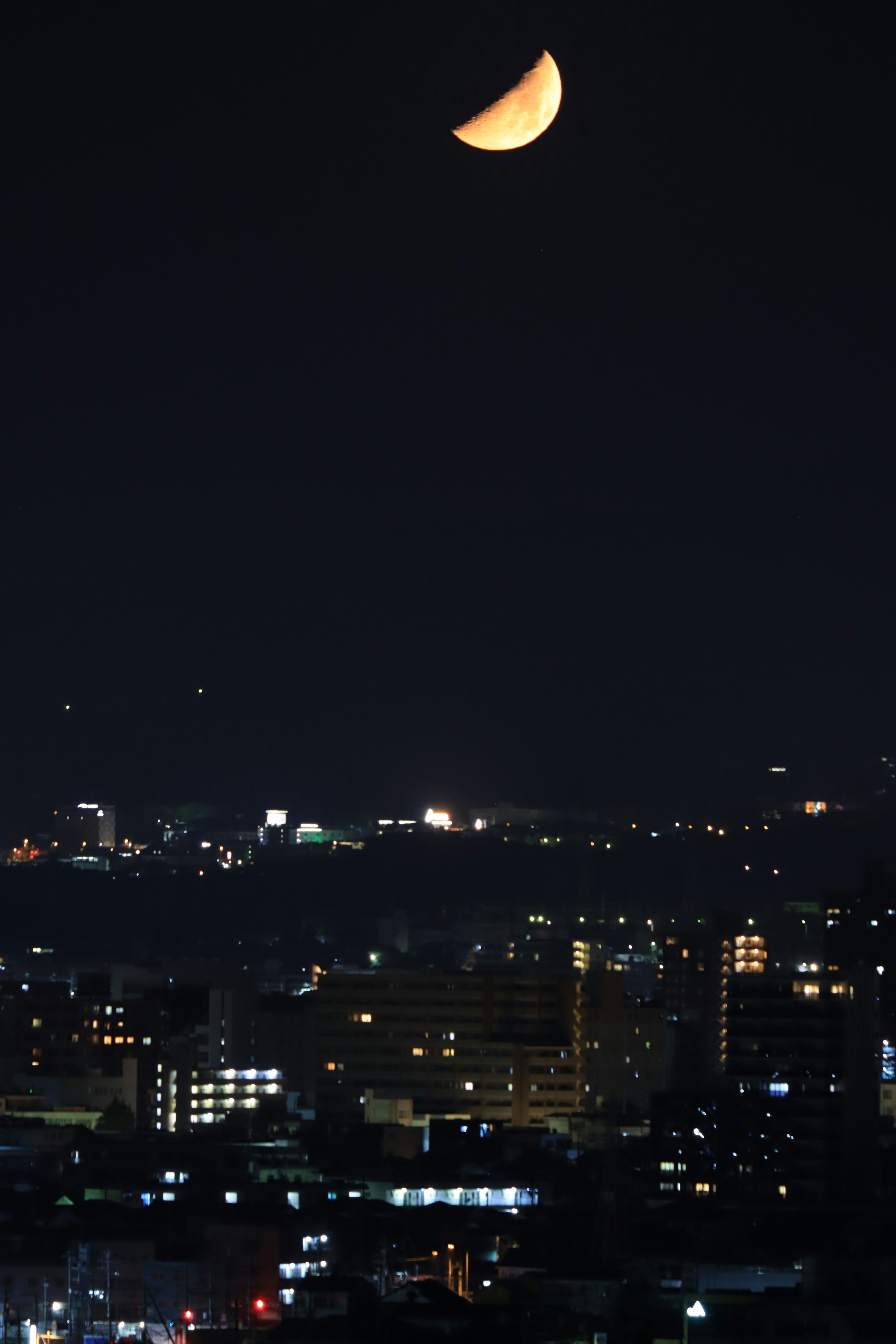 Luna creciente en el cielo nocturno sobre un paisaje urbano