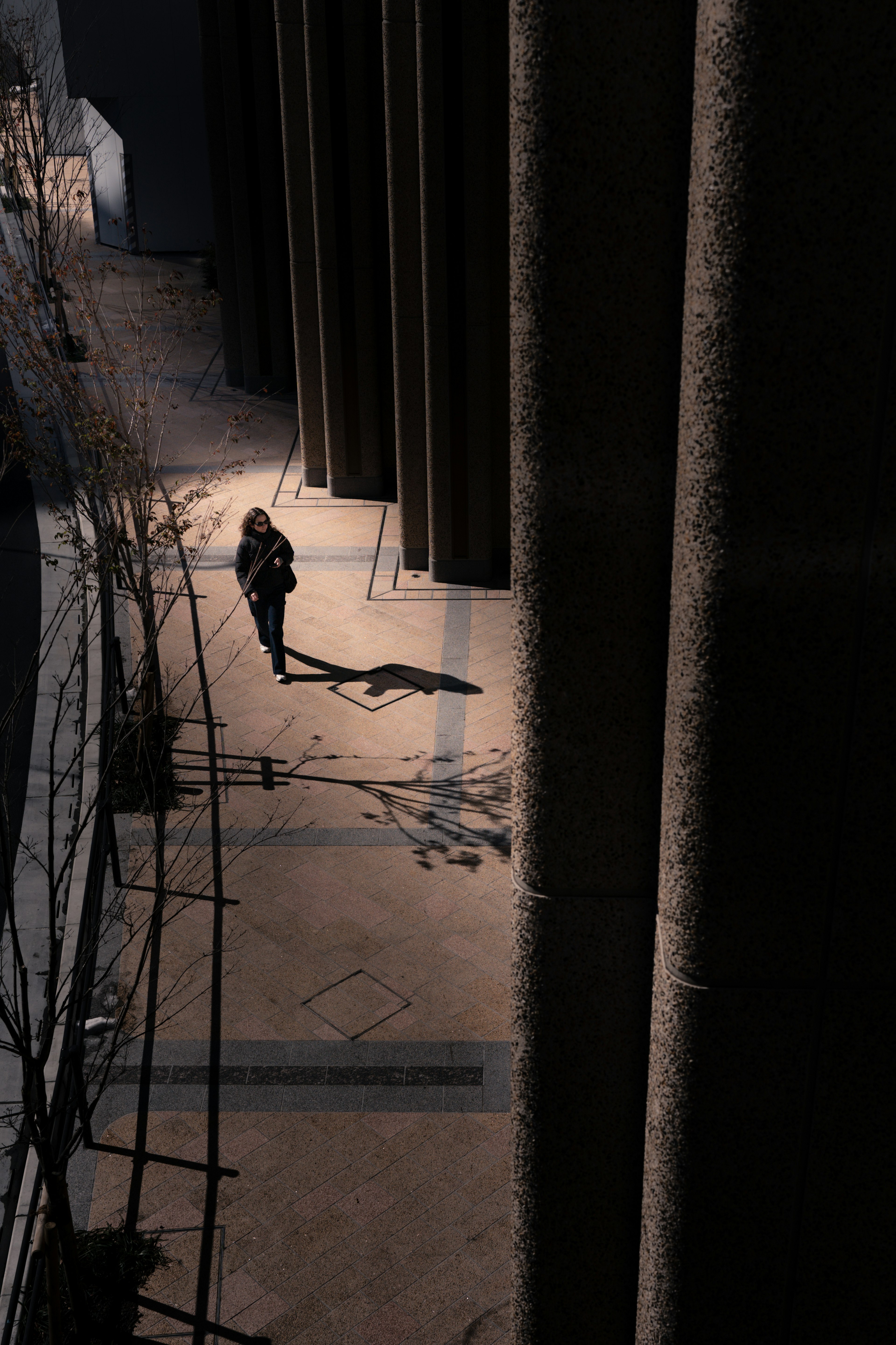 A figure standing in a dark corridor with shadows cast on the ground