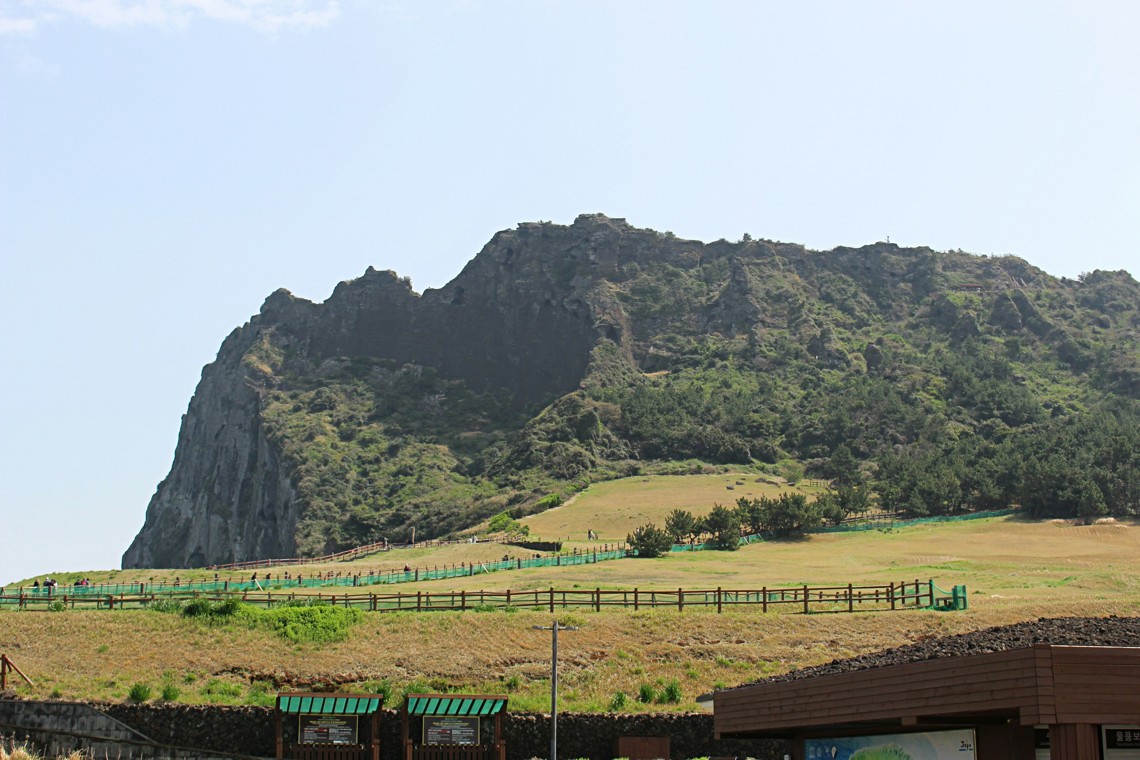 Una montaña rocosa con colinas verdes bajo un cielo azul