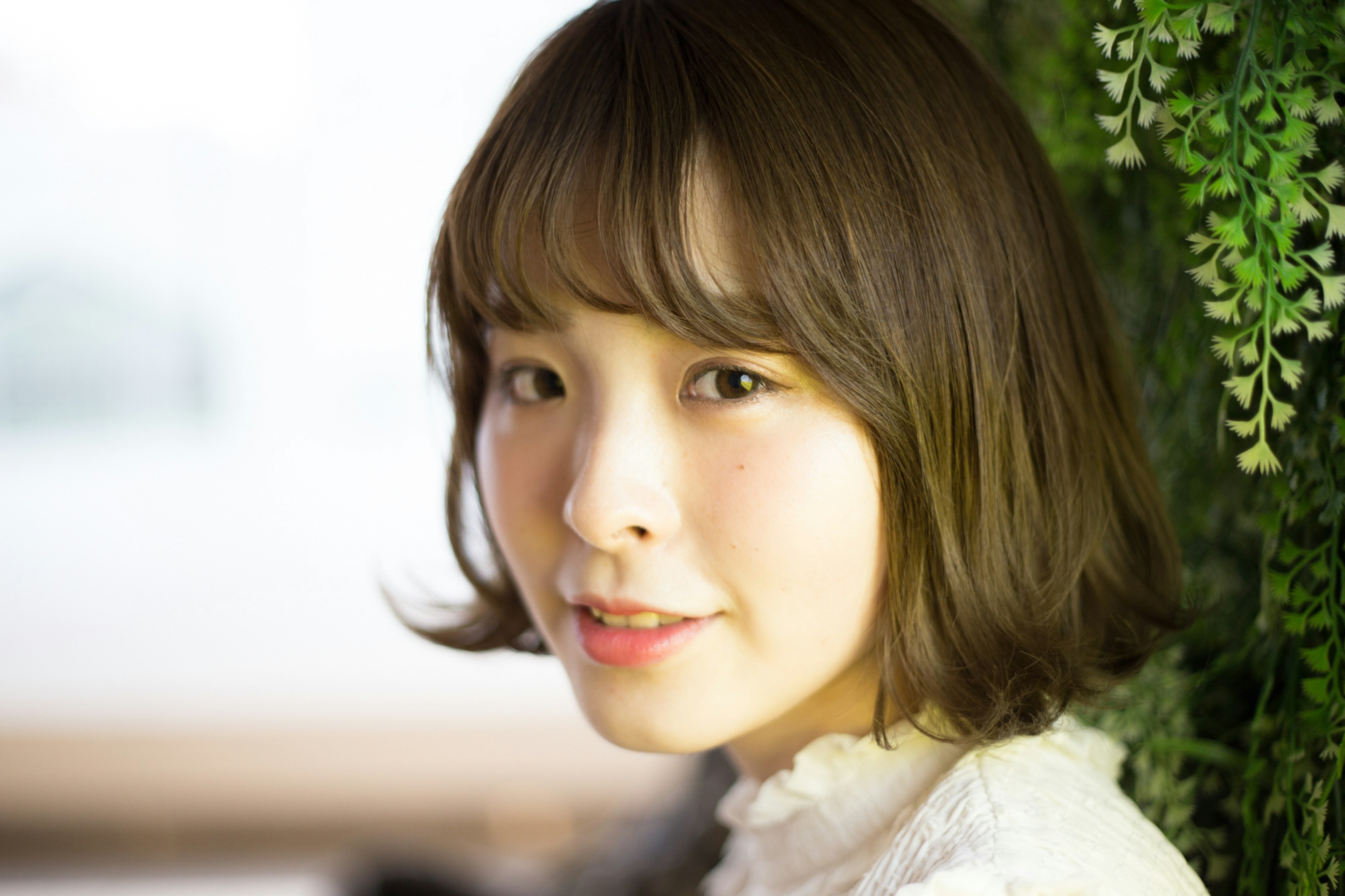 Portrait of a woman with a soft expression and greenery in the background