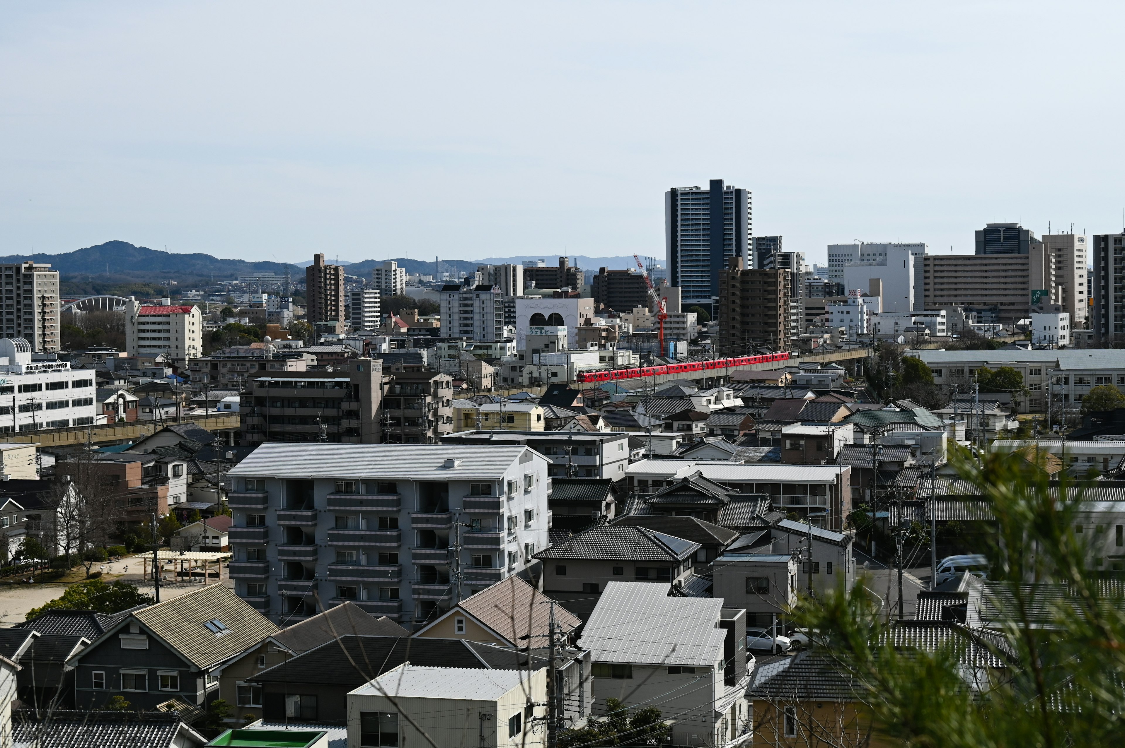 Cityscape showing a mix of buildings and houses with mountains in the background