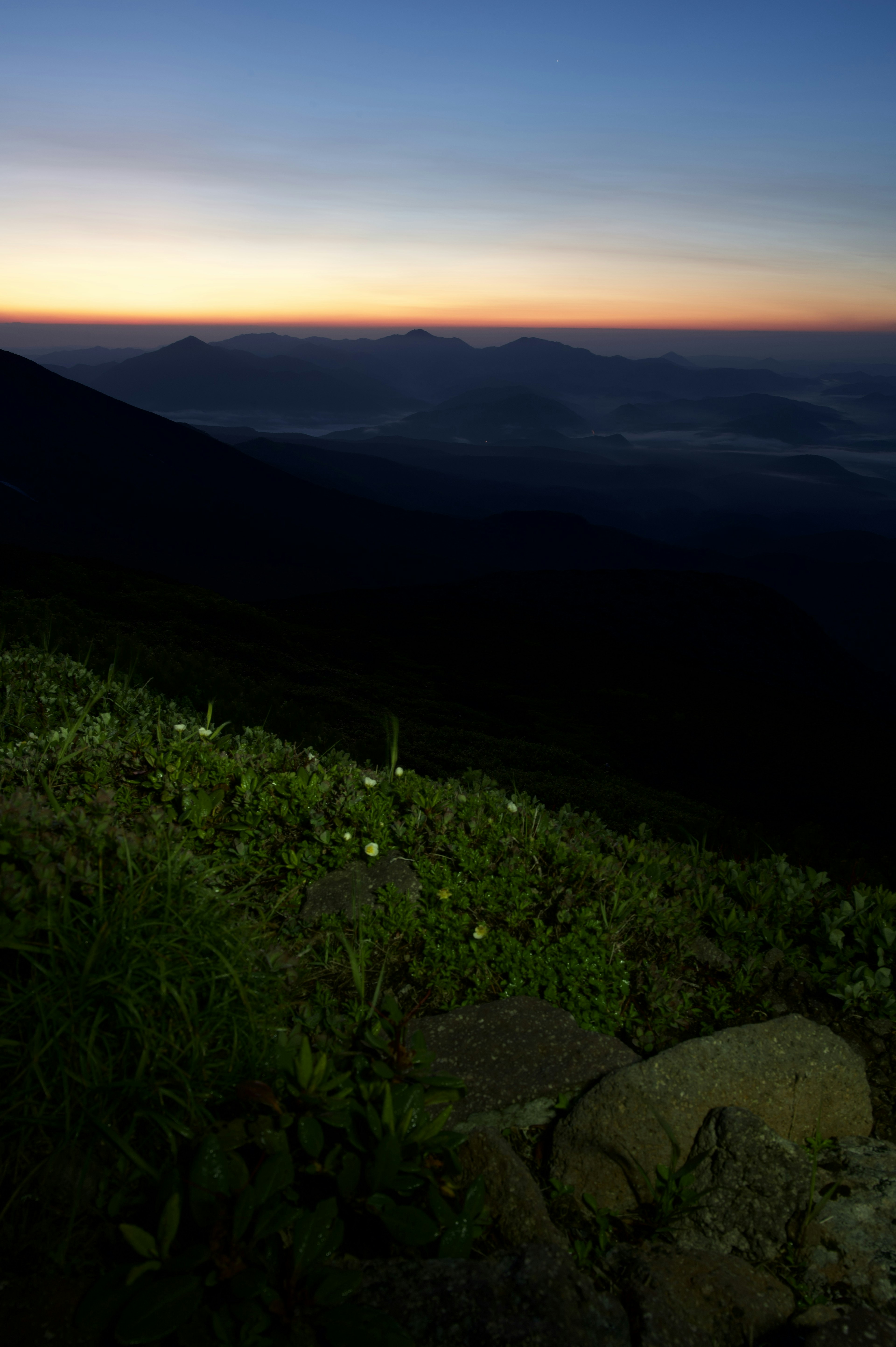 Paisaje montañoso con cielo de amanecer hierba verde y primer plano de piedra