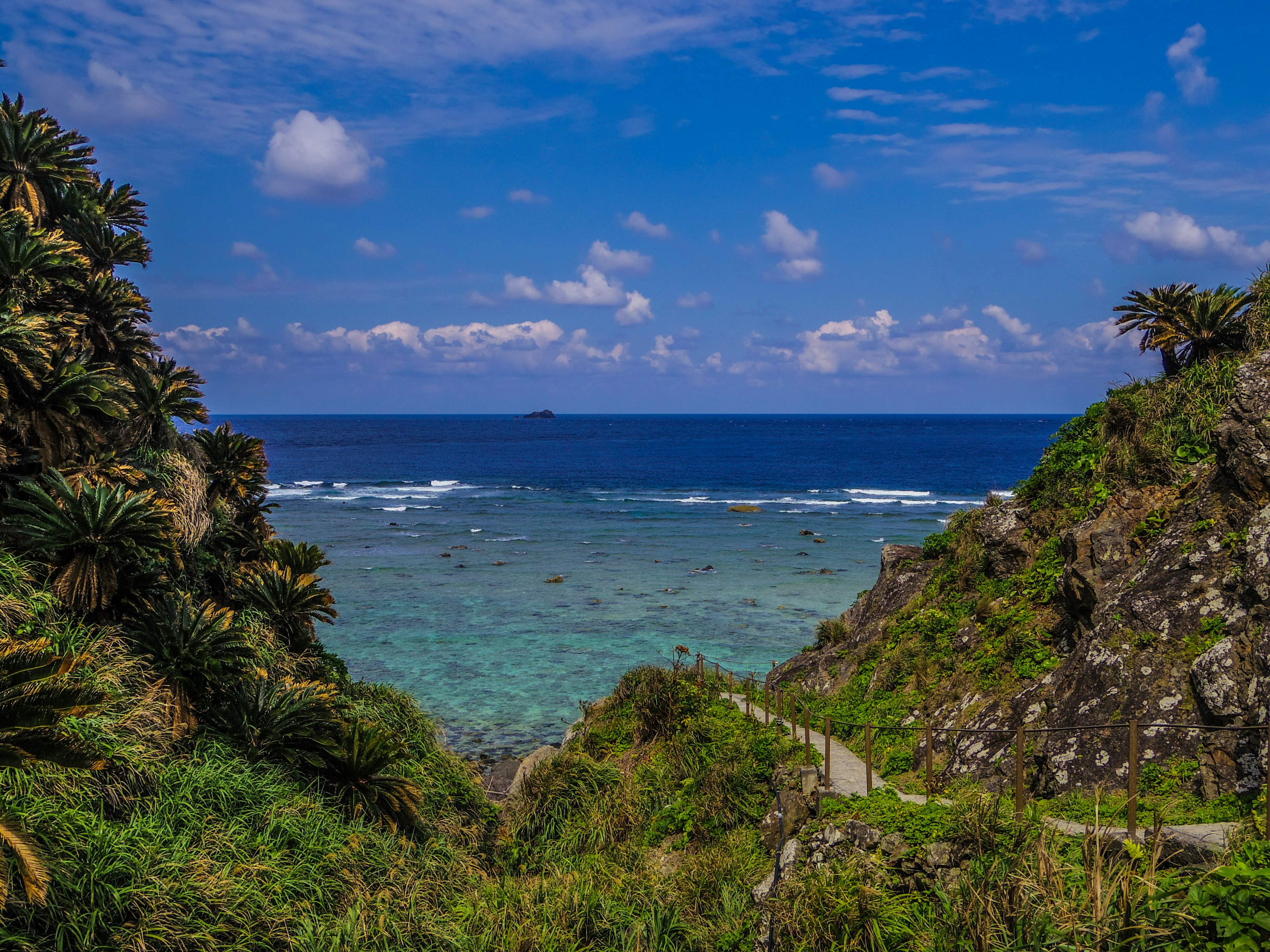 Scenic view of green hills leading to a blue ocean under a clear sky