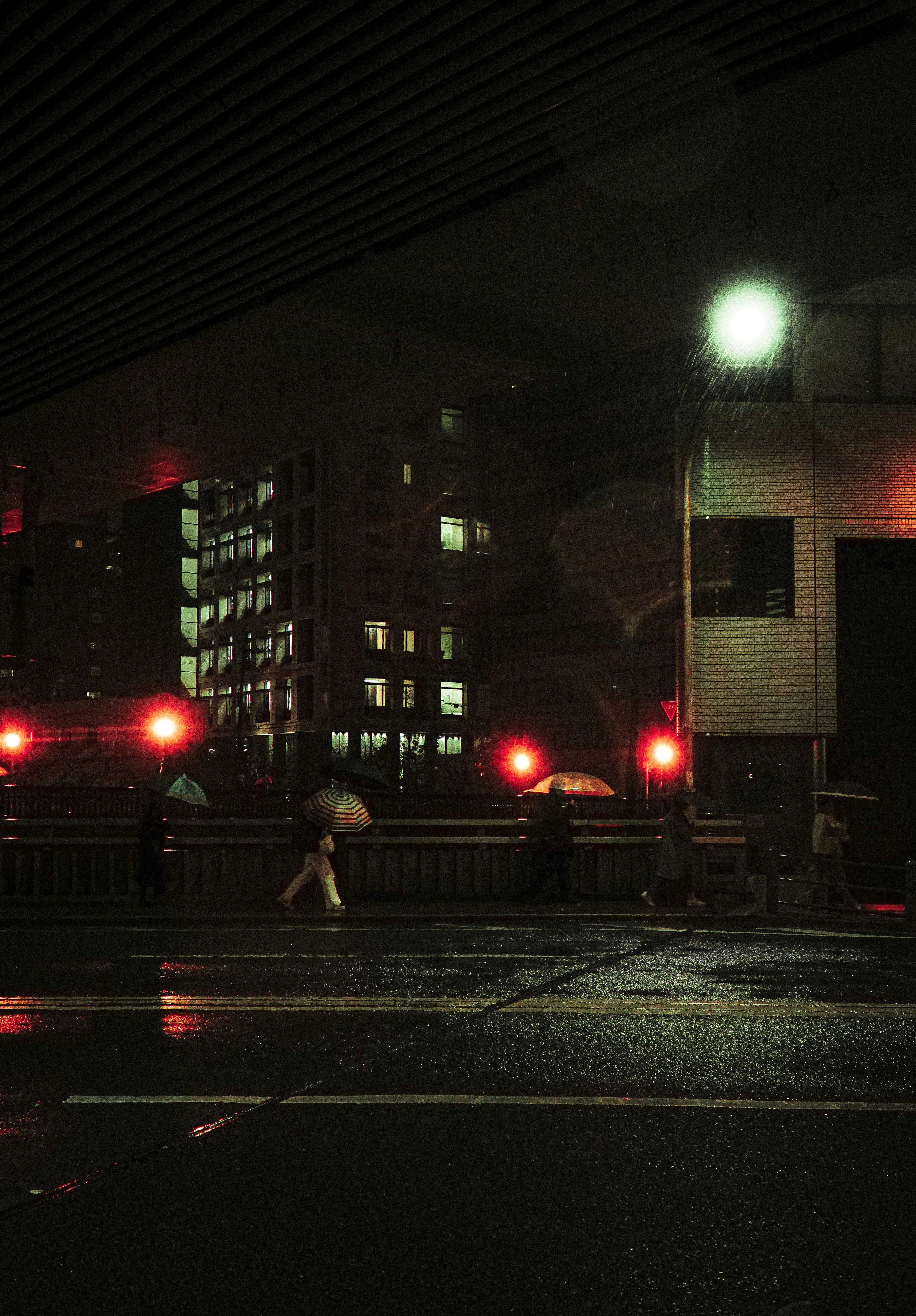 Paisaje urbano nocturno con carretera lluviosa semáforos rojos y peatones