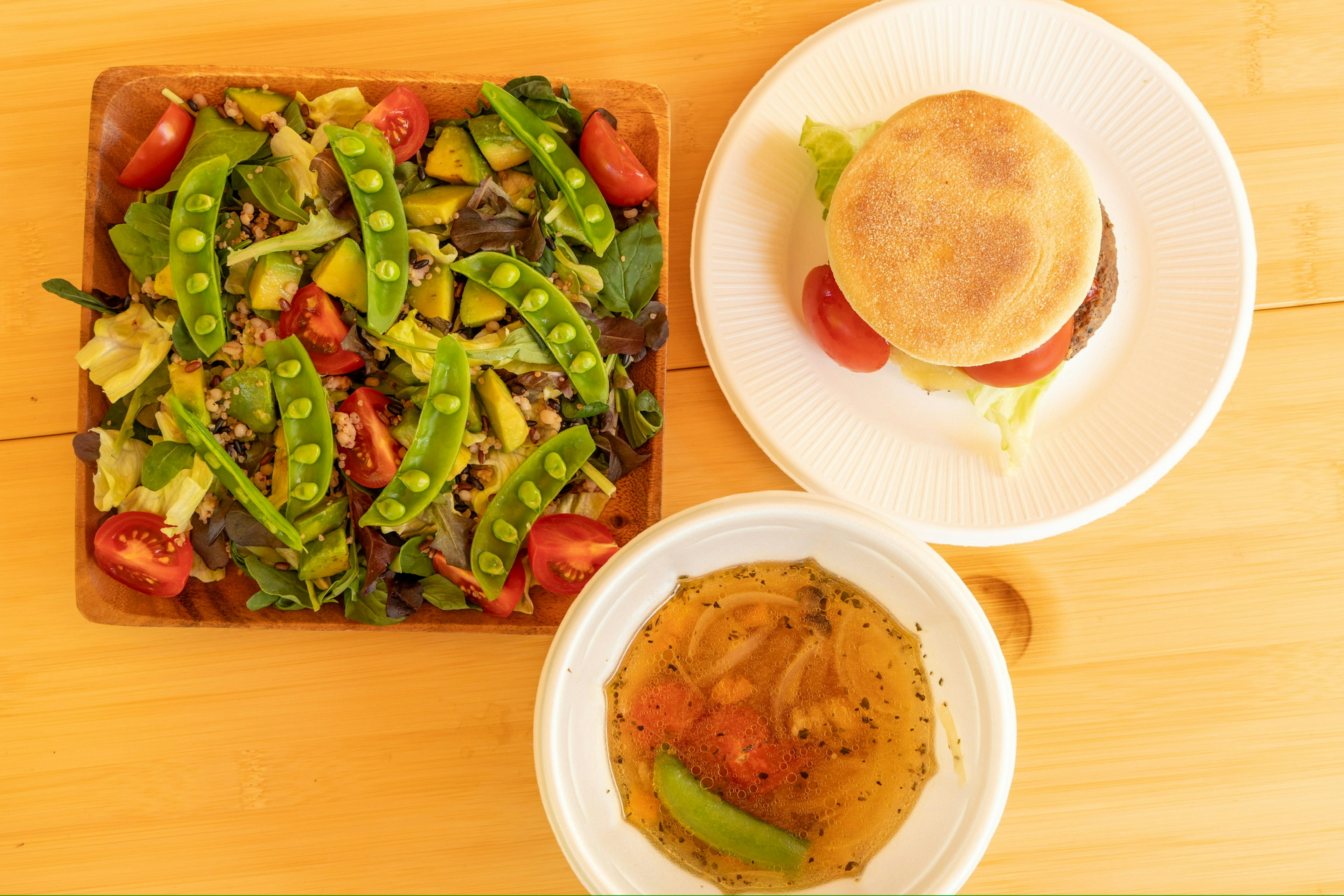 Un piatto con un'insalata di verdure fresche, zuppa e un panino