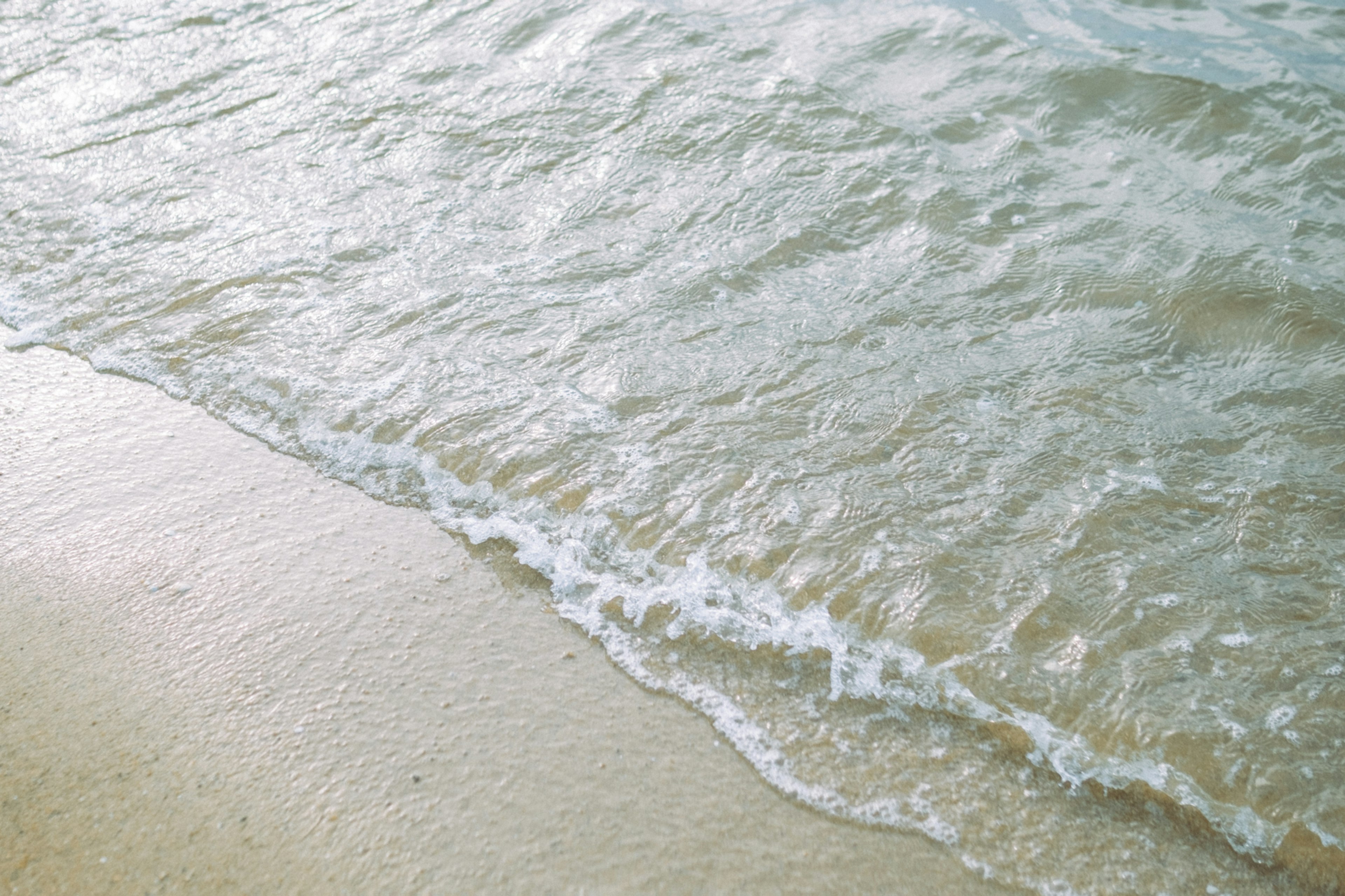 Onde calme che si infrangono su una spiaggia di sabbia