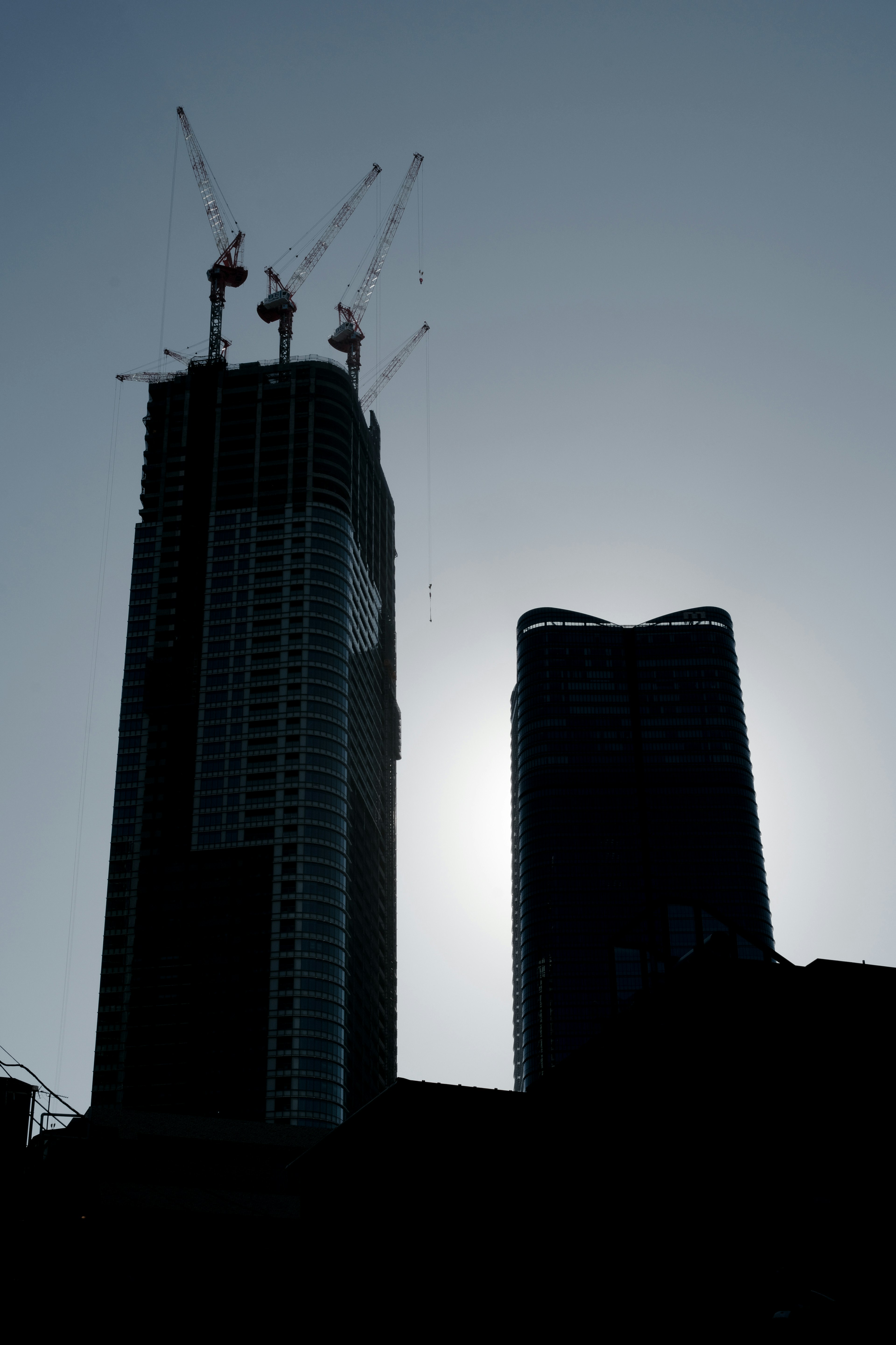 Silhouette of skyscrapers under construction against the backdrop of the sun