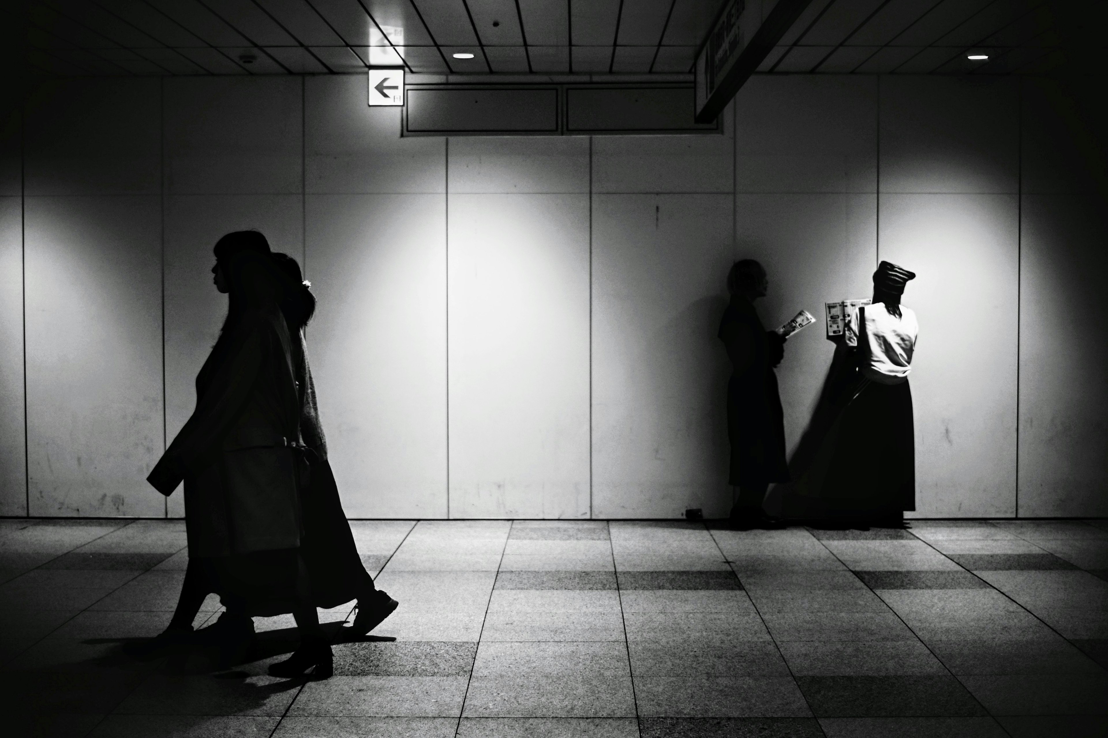 Silhouettes of people walking in a black and white urban setting