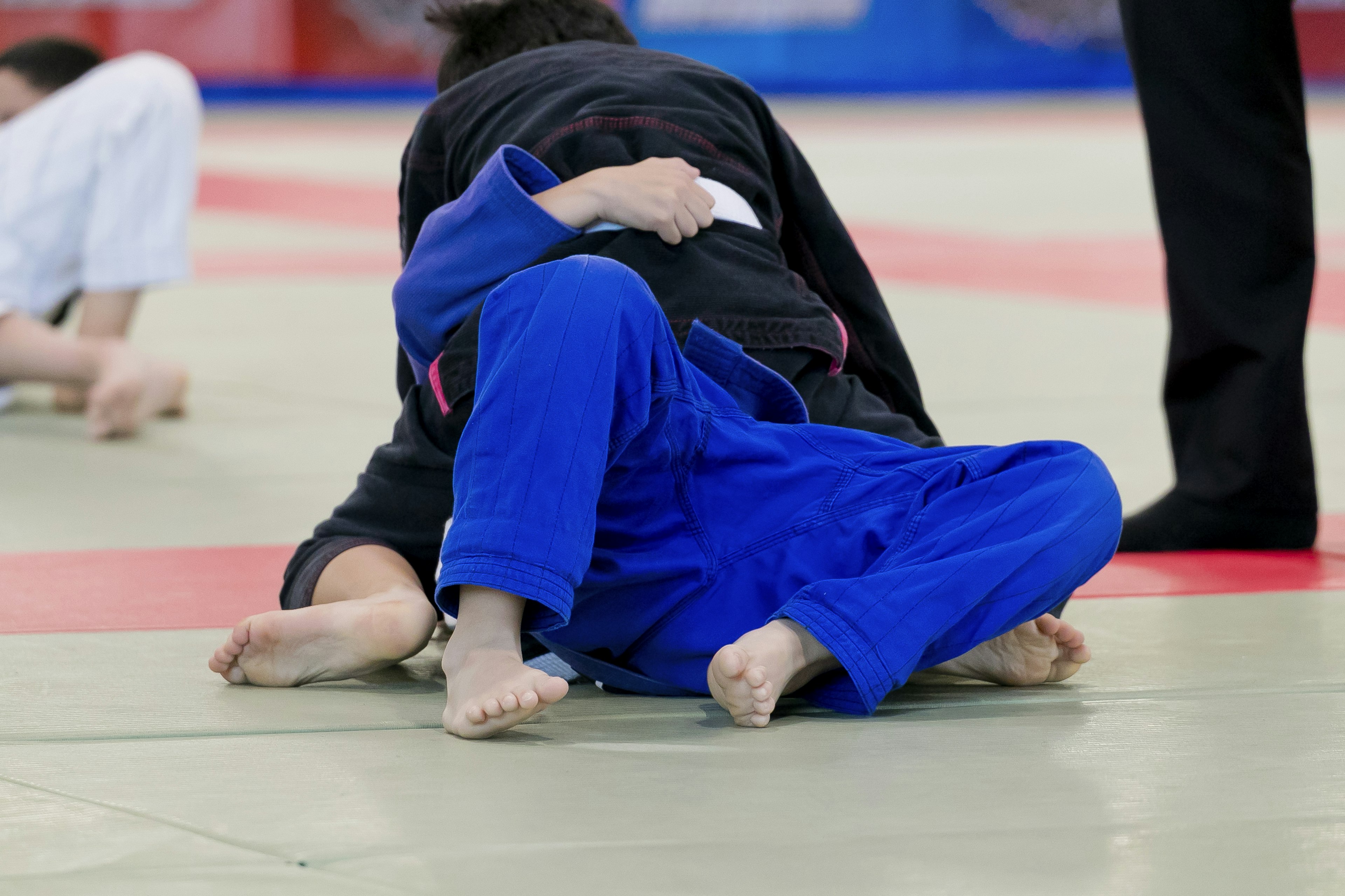 Un combate de judo mostrando a un competidor en gi azul en el suelo