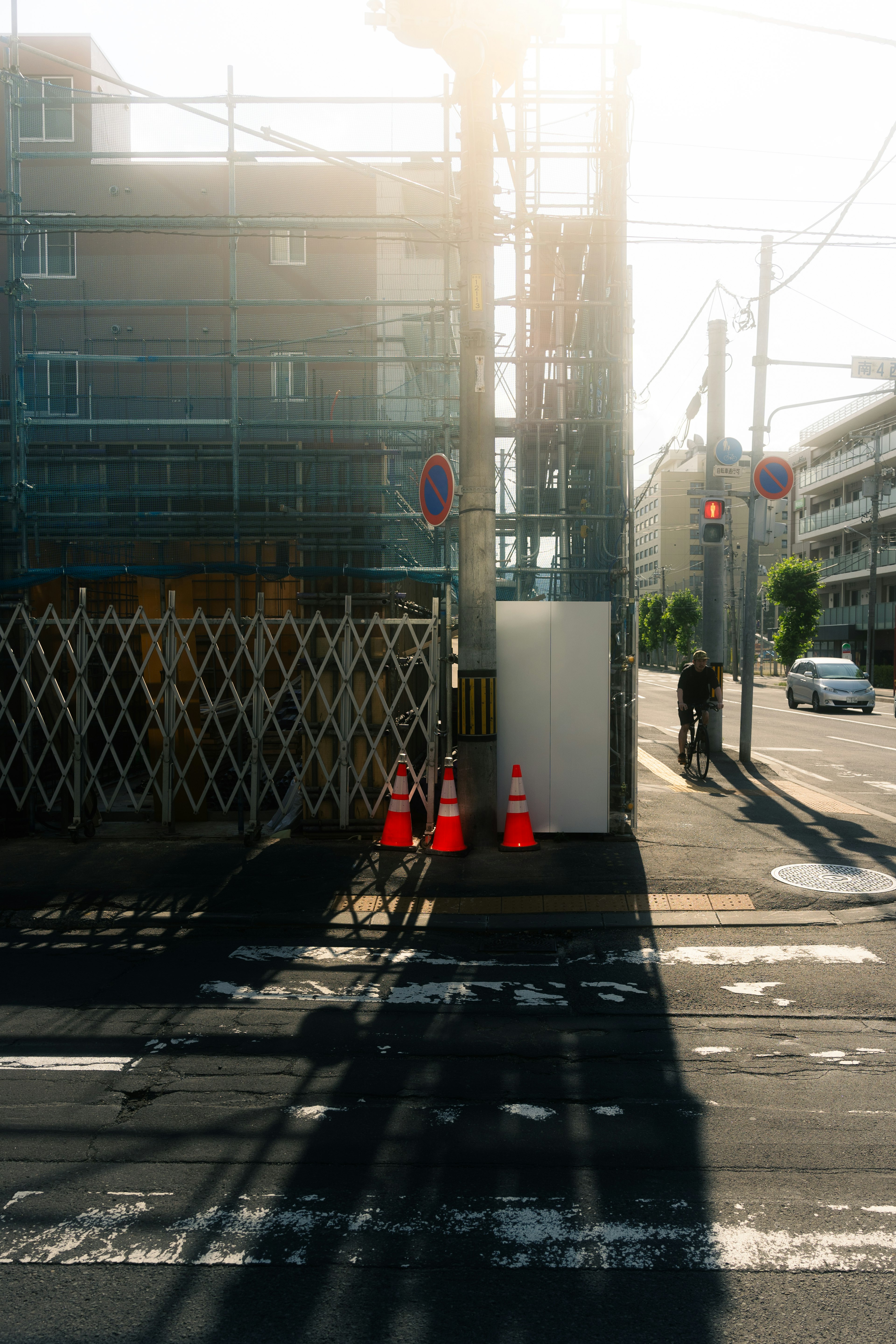 Construction site at street corner with orange cones sunlight streaming