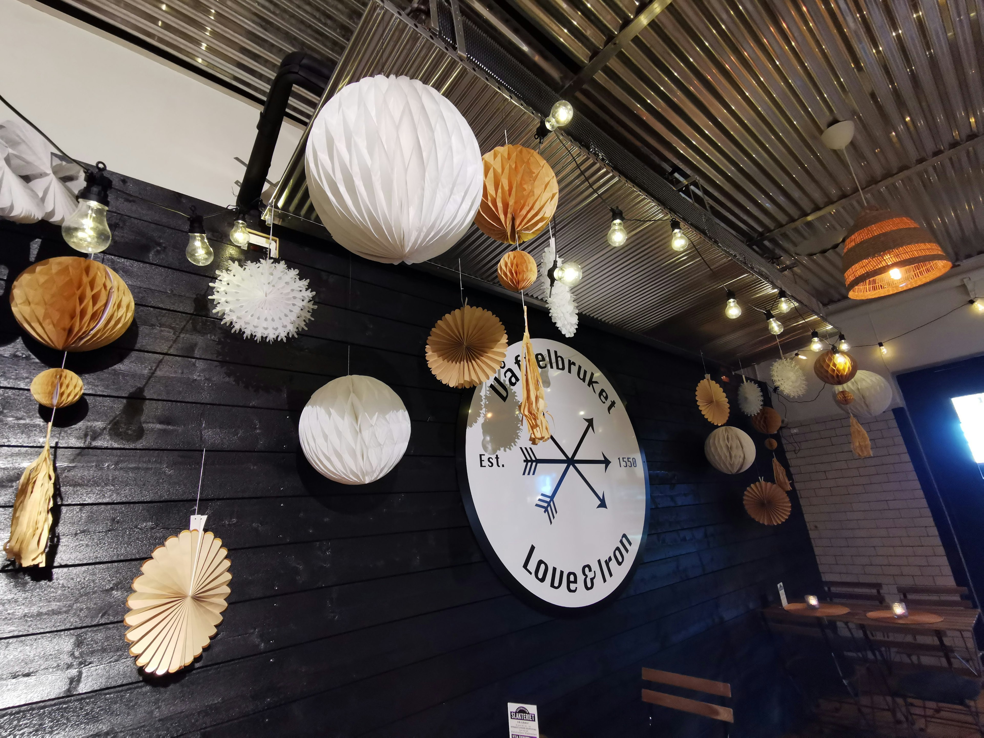 Cafe interior with white and brown decorative hanging items on a black wall