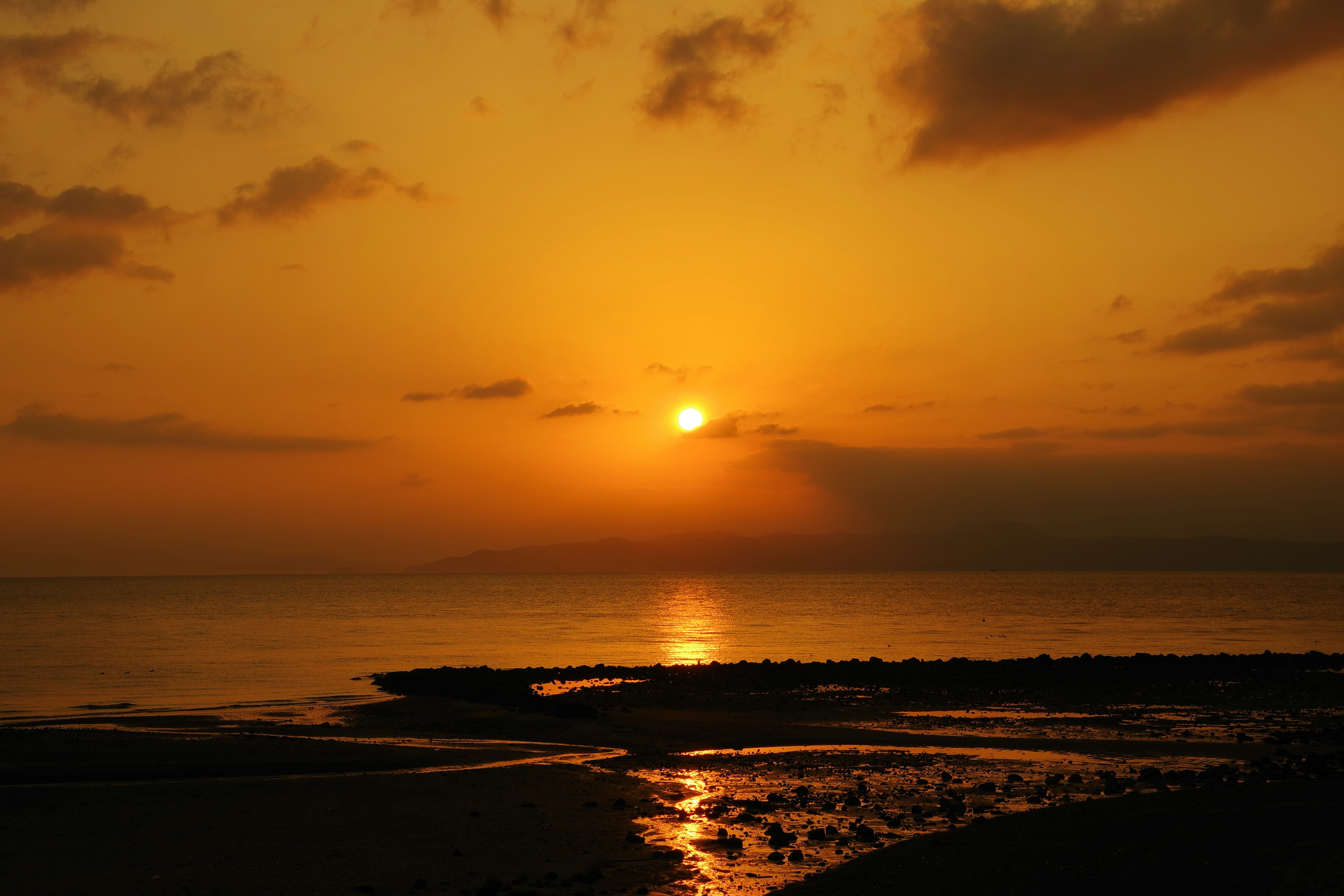 Sunset over the ocean with orange sky calm waves and reflected sunlight