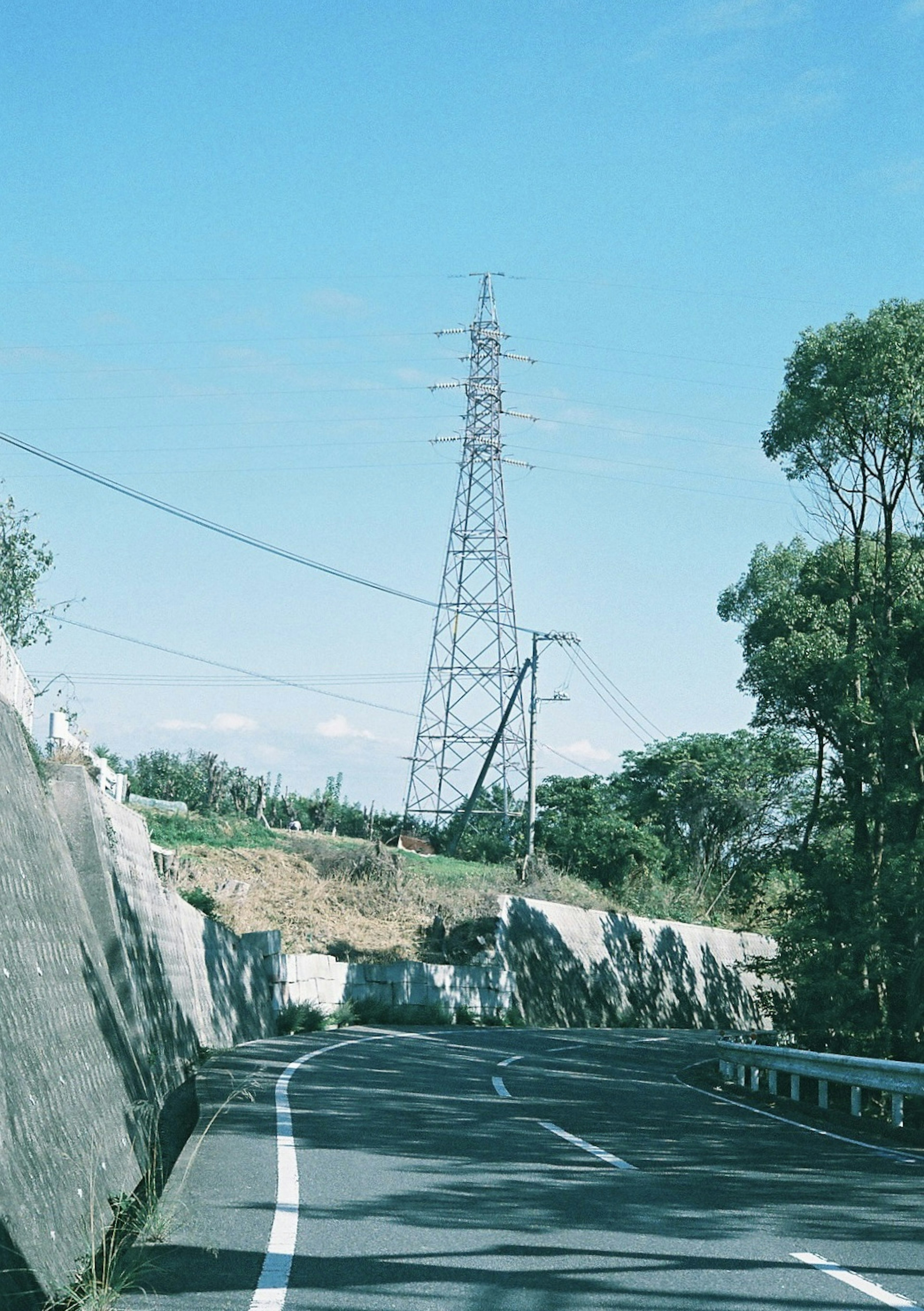 Vue pittoresque d'une route sinueuse avec une grande tour de transmission sous un ciel bleu