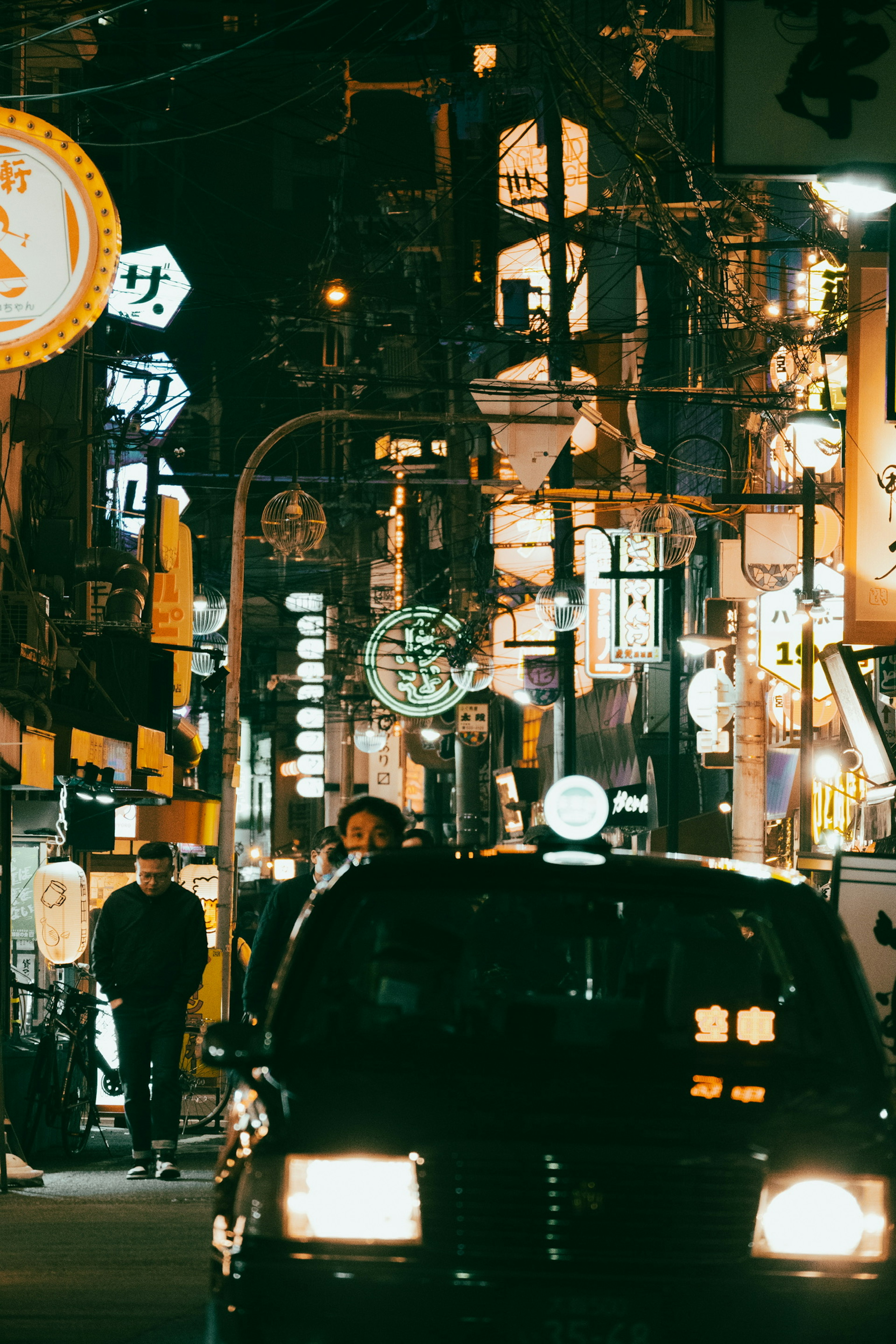 Street scene at night with a taxi and neon signs in a bustling area