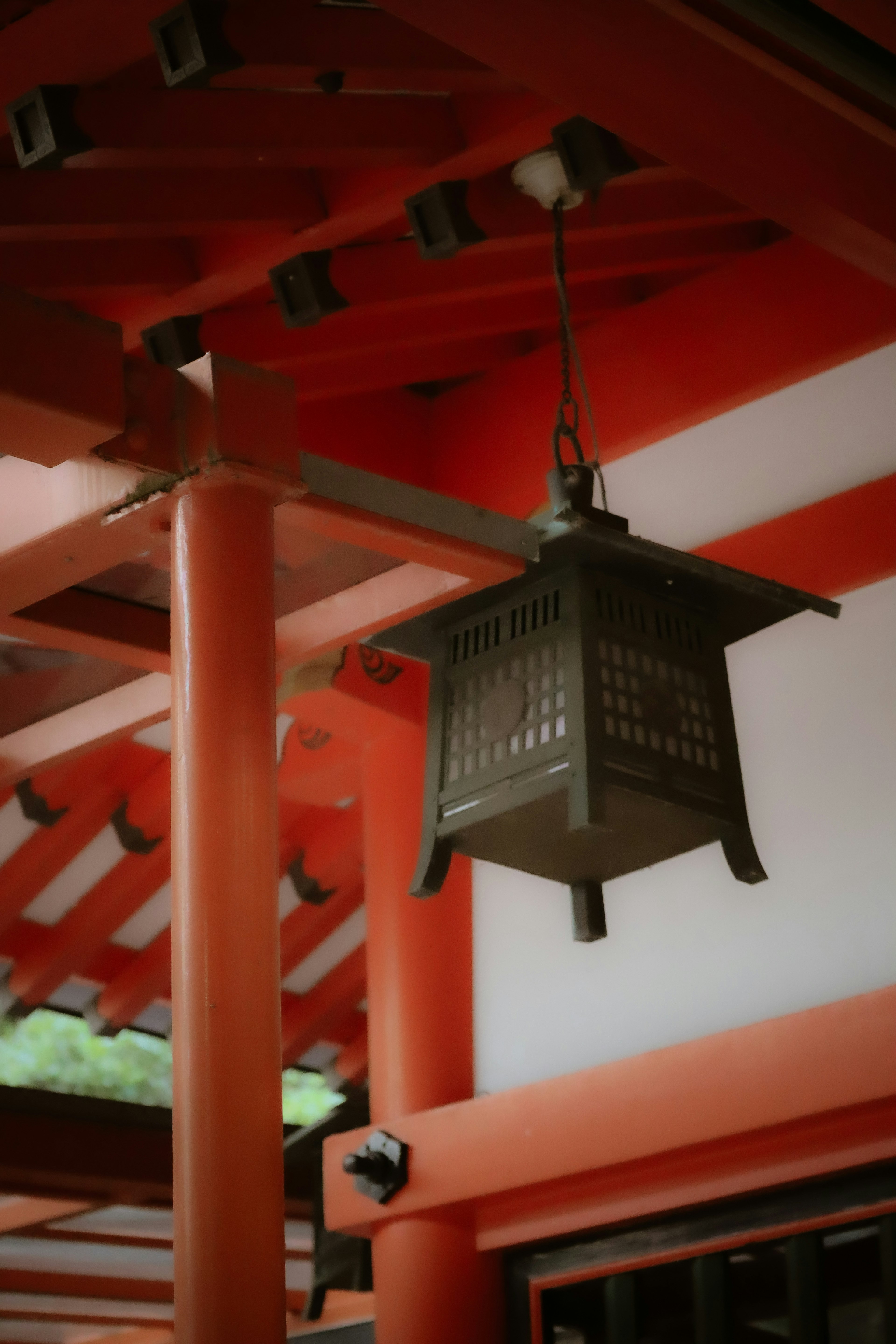 Lanterne japonaise traditionnelle suspendue sous des poutres rouges