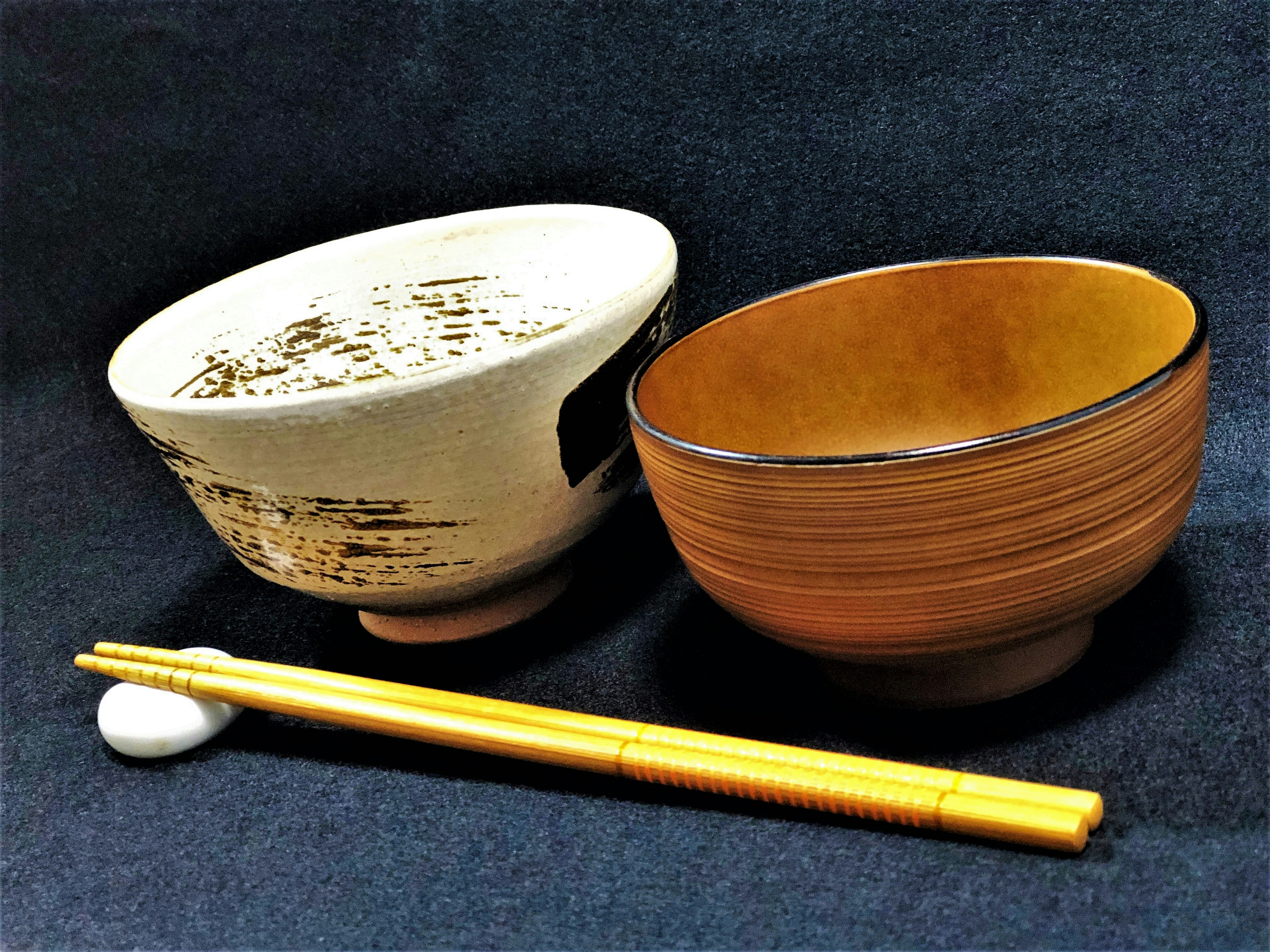 Image of a white Japanese bowl and a brown bowl next to each other with chopsticks