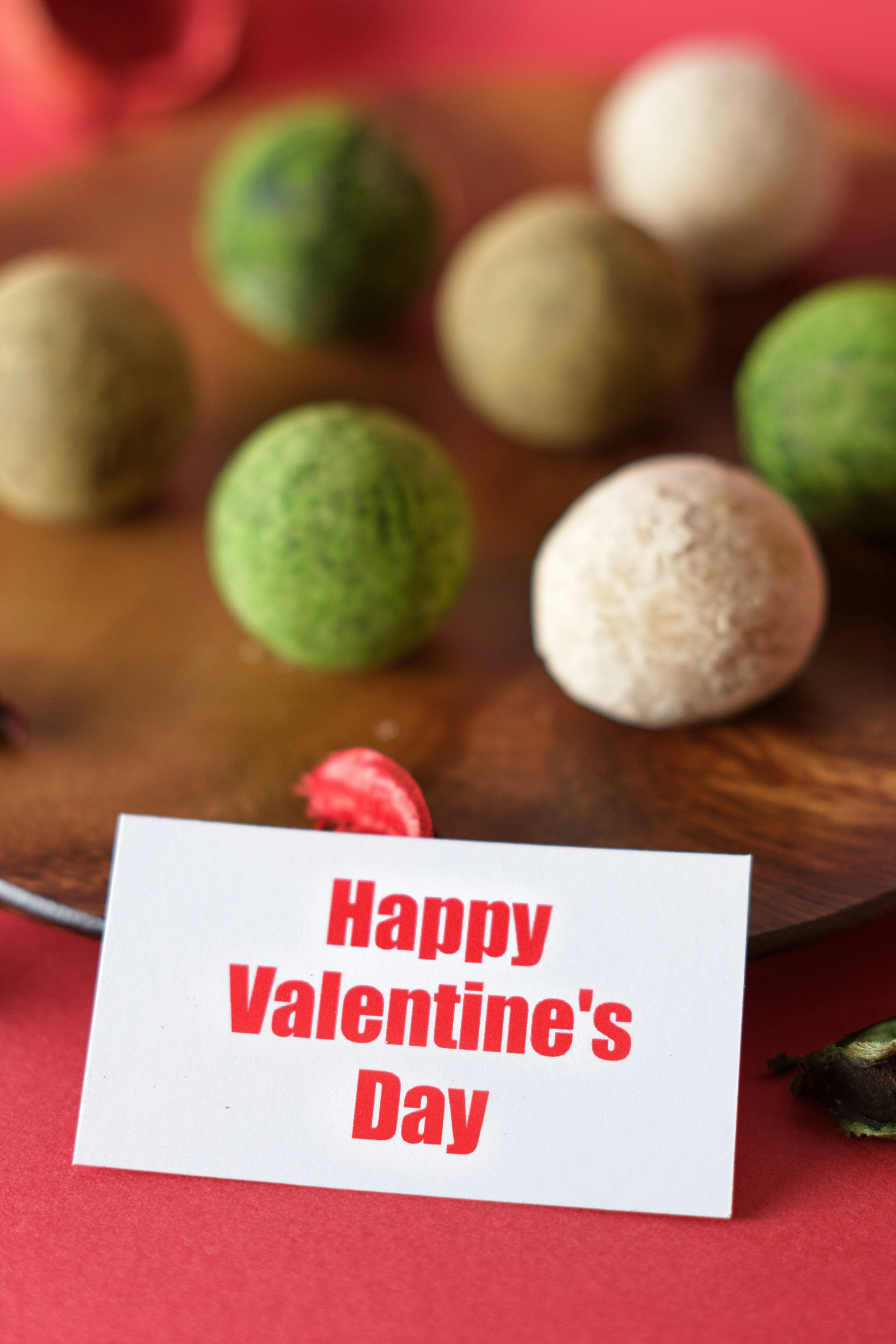 A card saying Happy Valentine's Day with colorful balls on a wooden plate