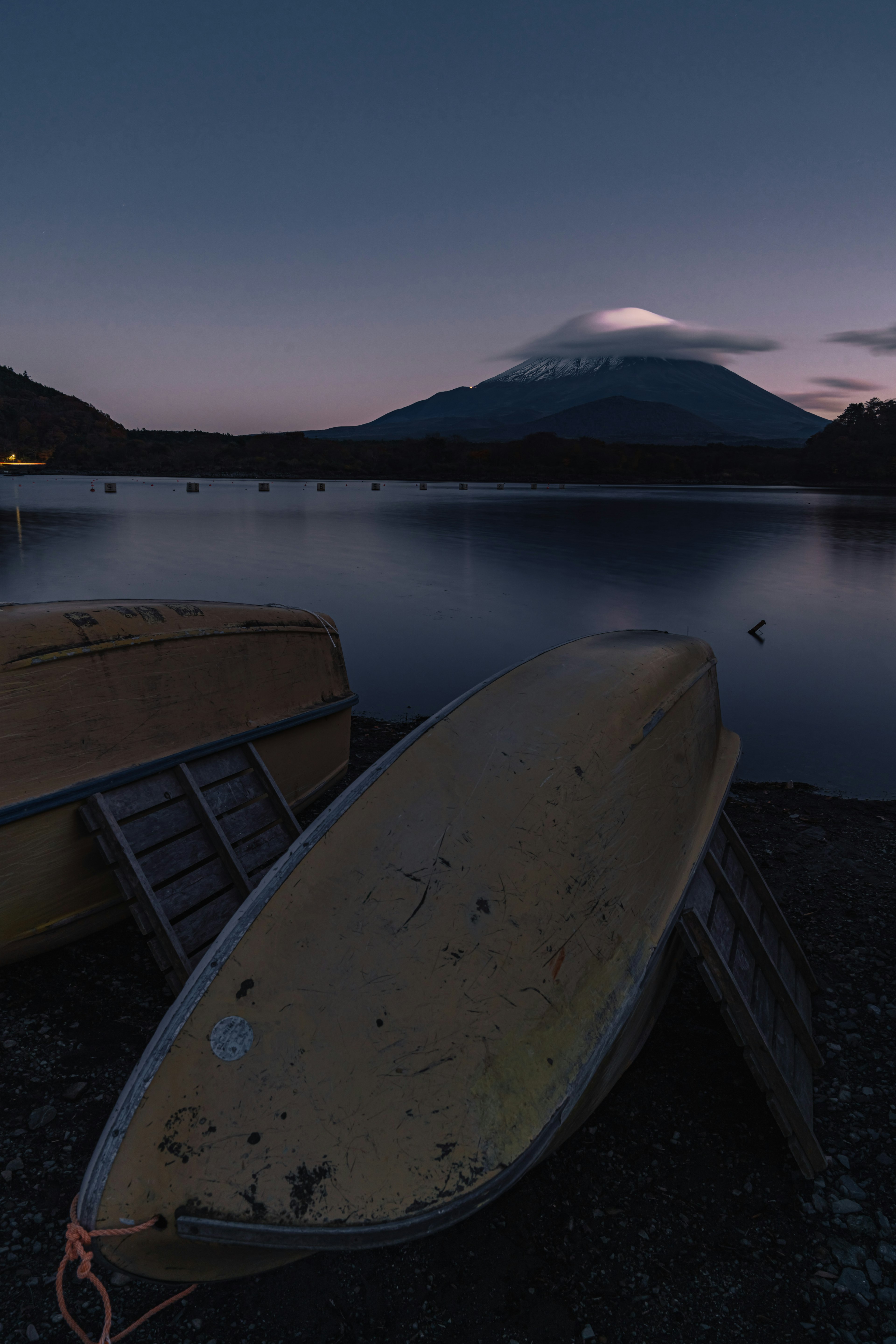 夕暮れの湖に浮かぶボートと山の風景