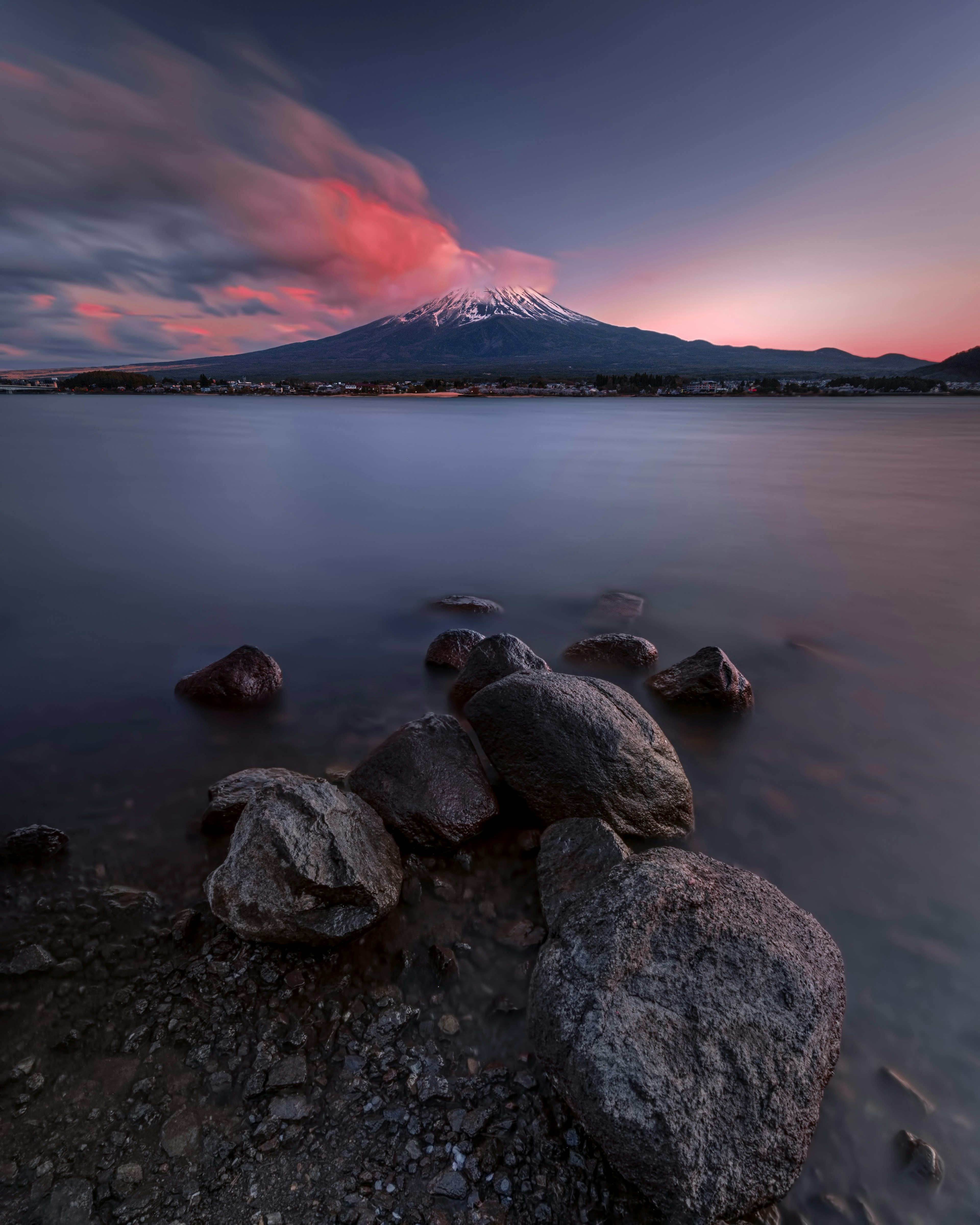 美しい山と静かな湖の風景 朝焼けの空が反射し大きな岩が湖岸にある