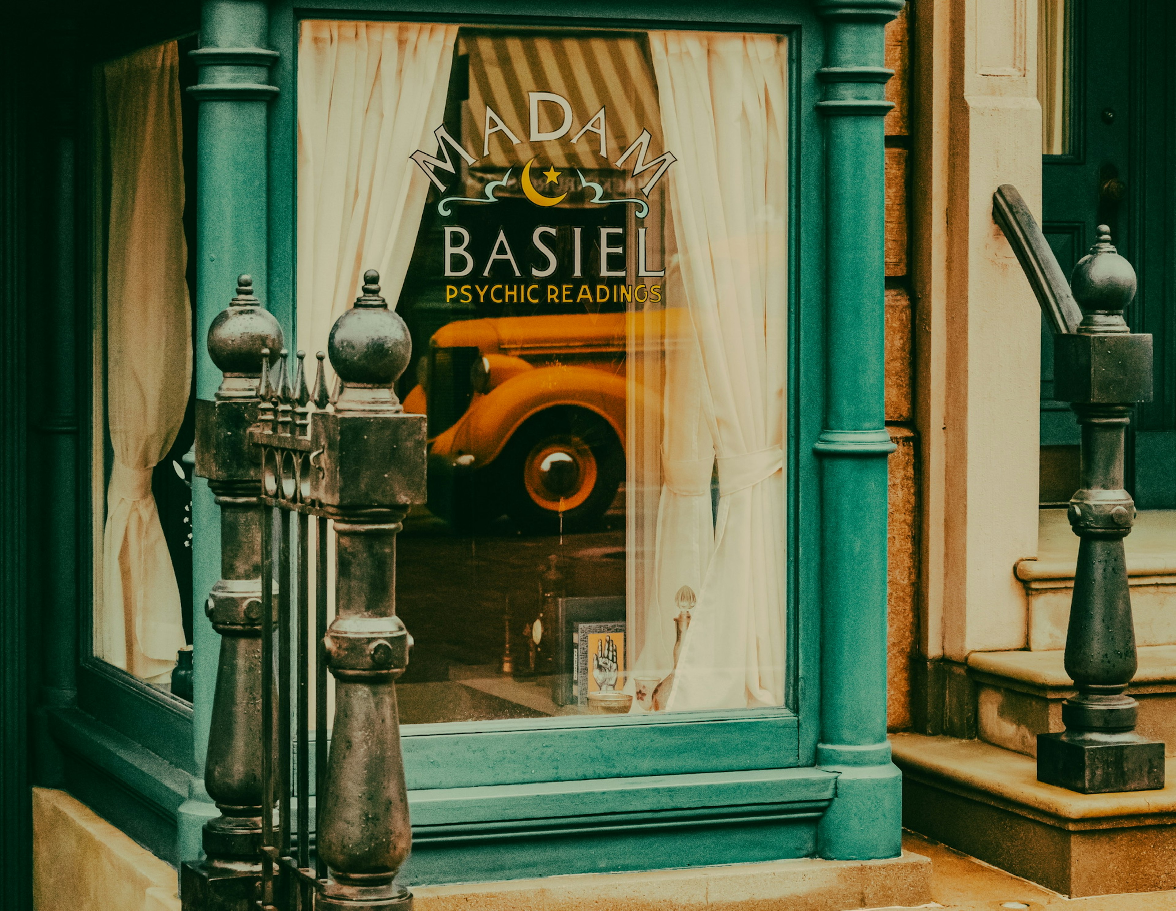 Fenster eines Wahrsagerladens mit blauer Fassade und weißen Vorhängen