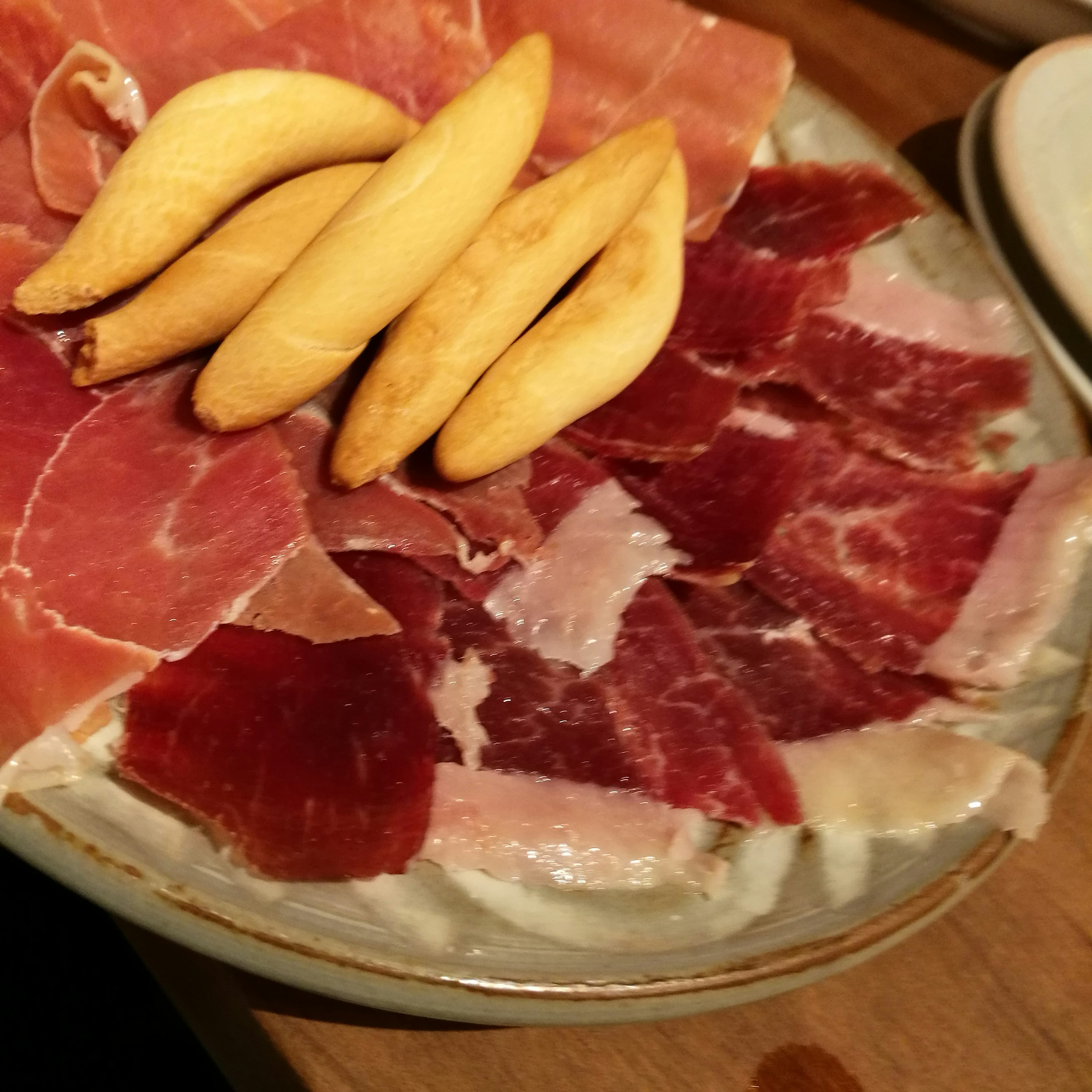 Plate of assorted cured meats including ham and a few small fruits