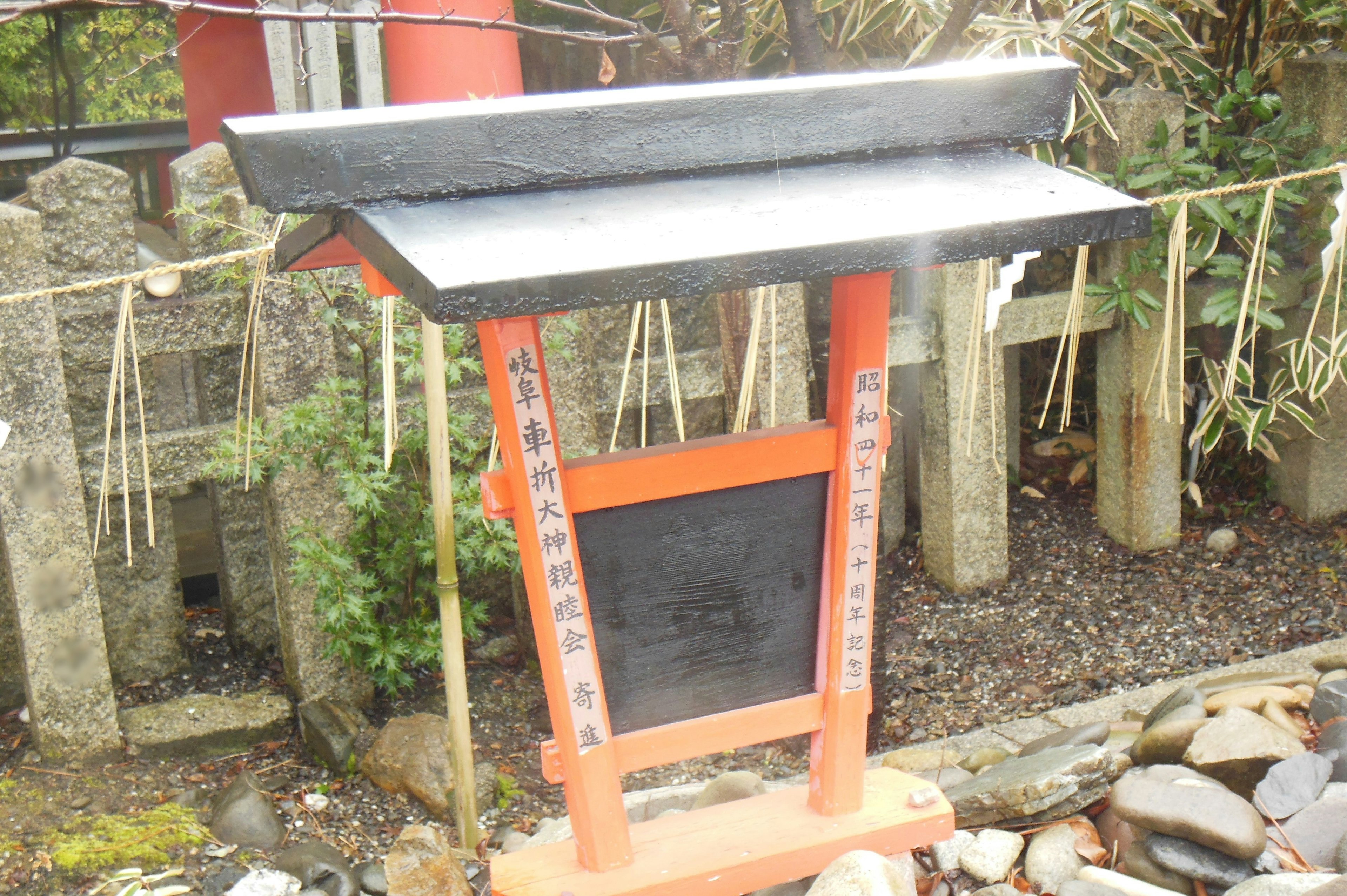 Immagine di un cartello nero vicino a un torii rosso