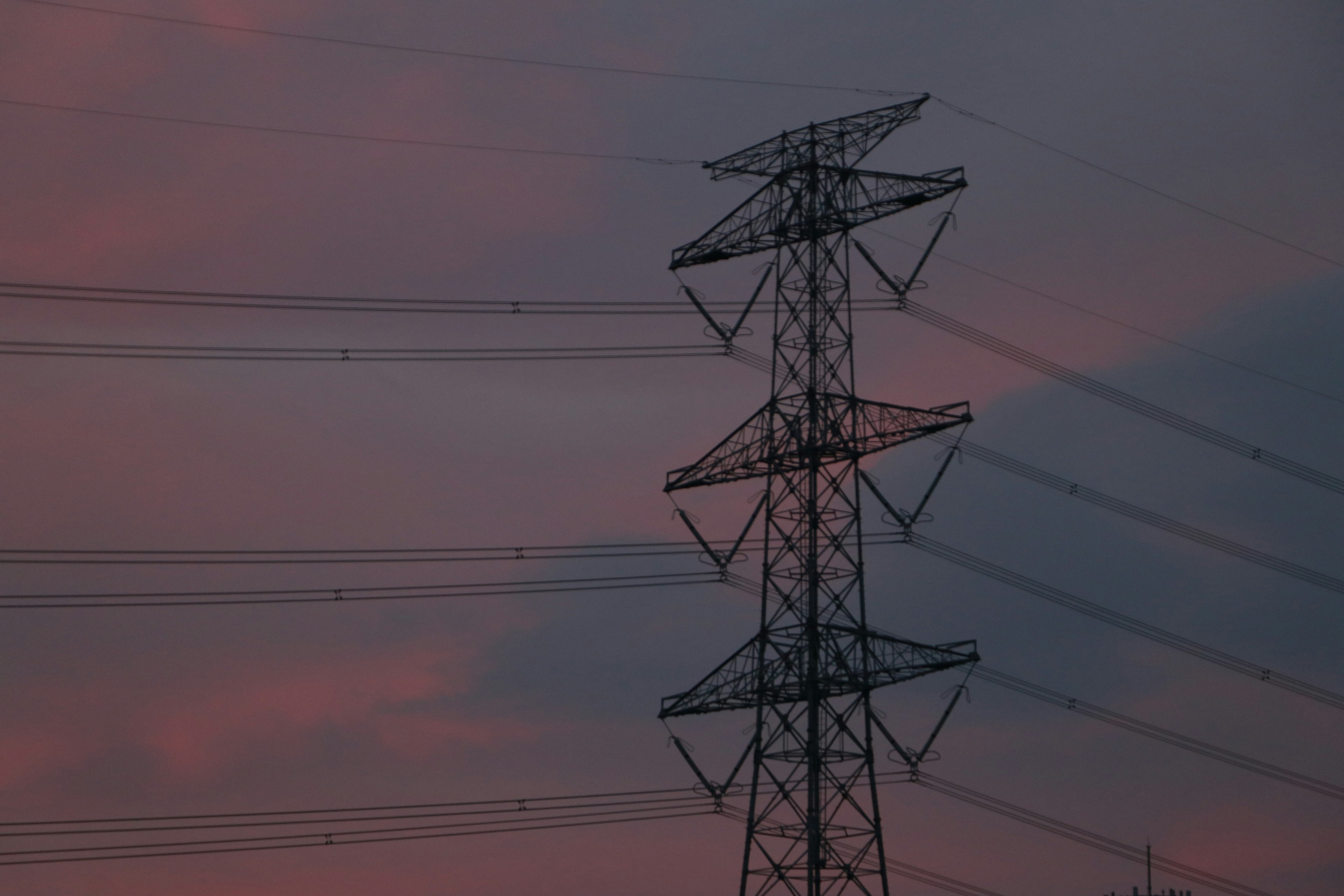 Power lines and tower silhouetted against a sunset sky