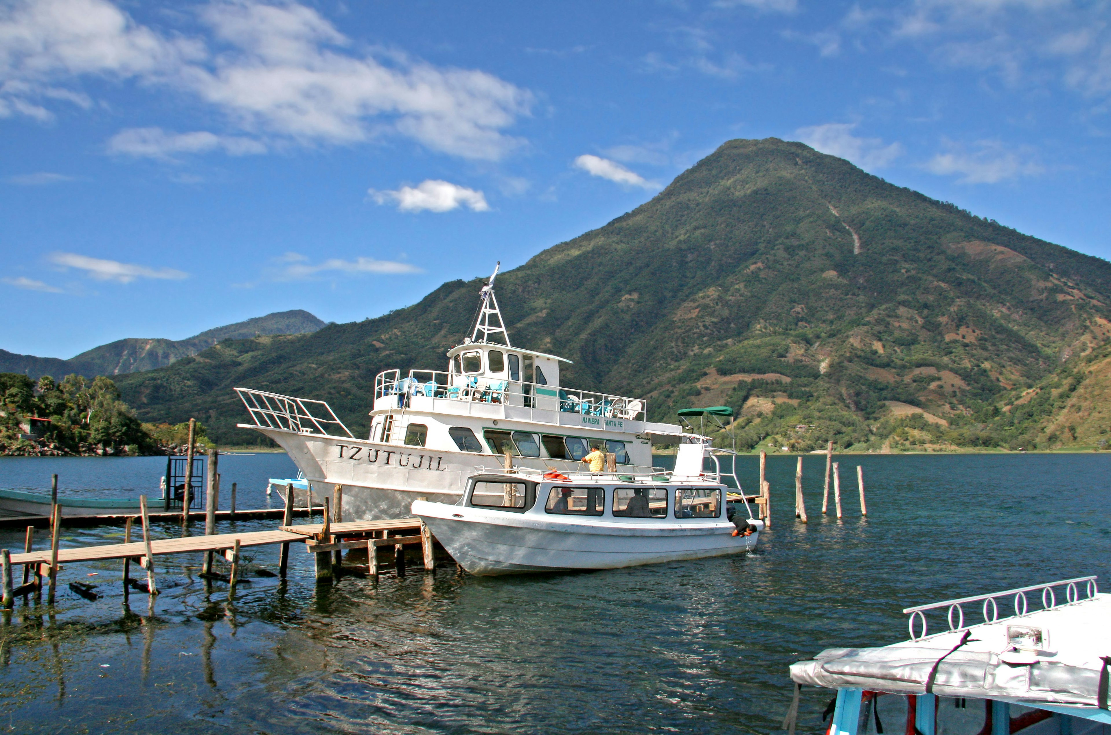 Un barco blanco atracado junto a un hermoso lago con un fondo montañoso