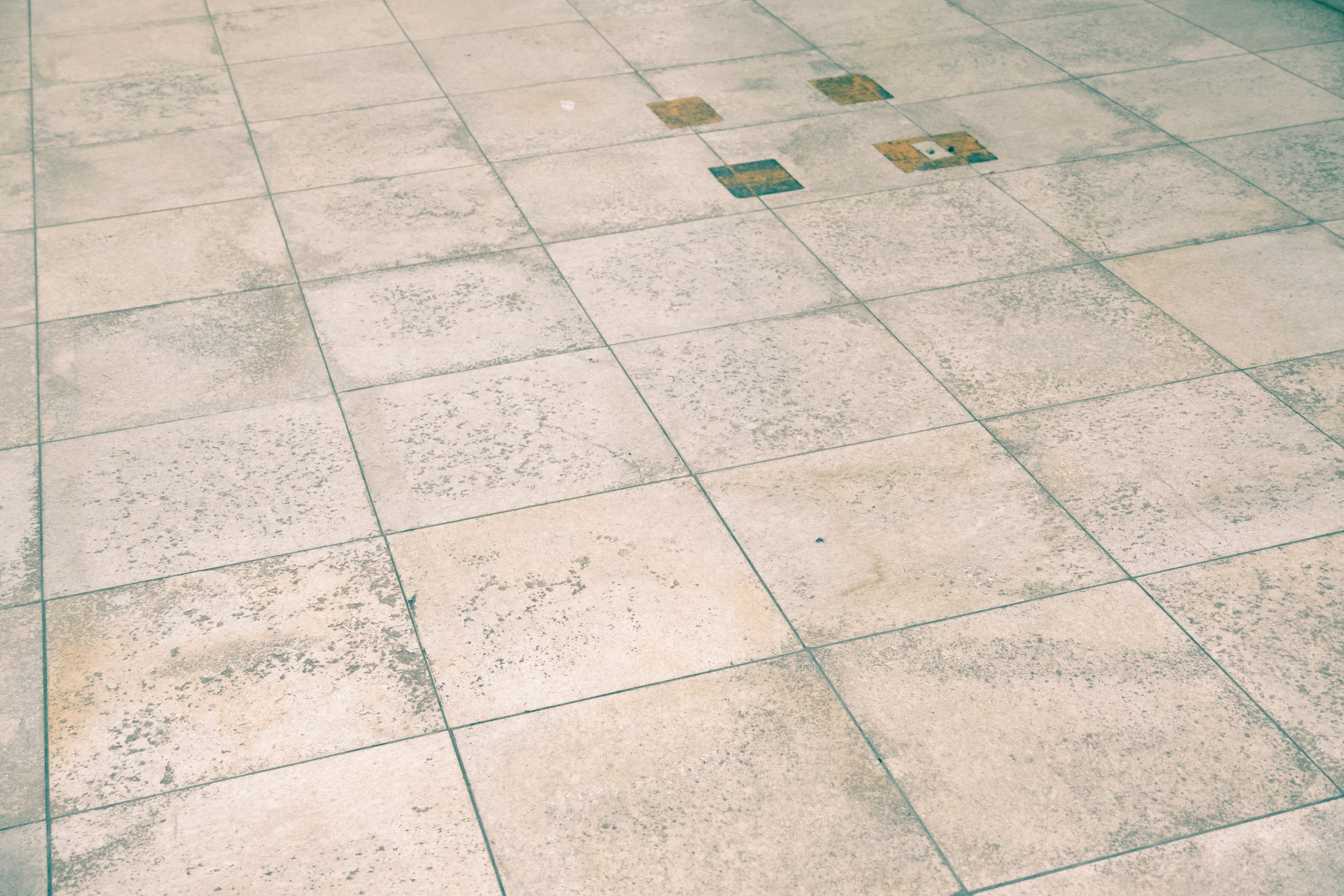 Image of a floor with light-colored tiles featuring some discoloration in several tiles