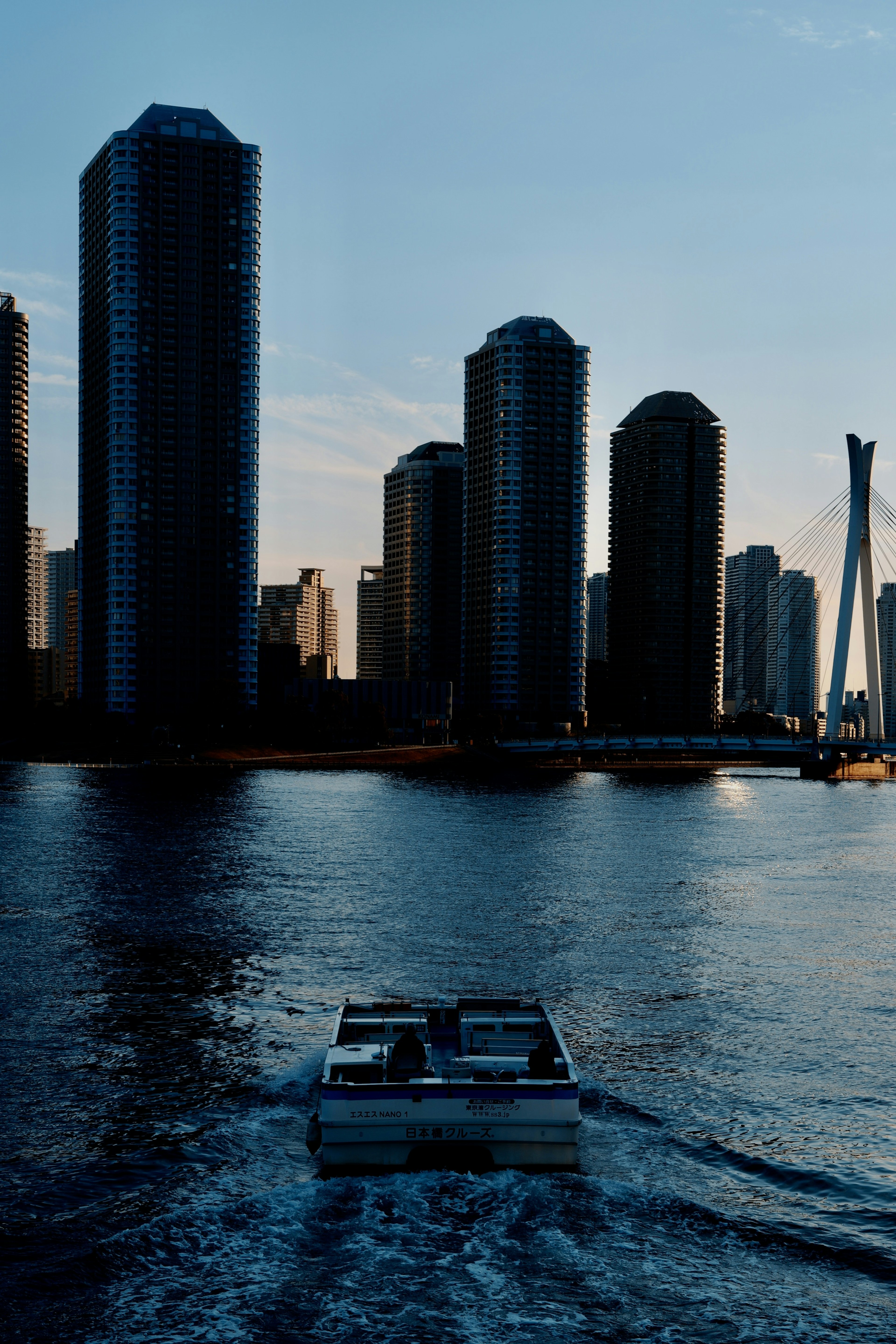 Boat gliding on water with skyscrapers in the background