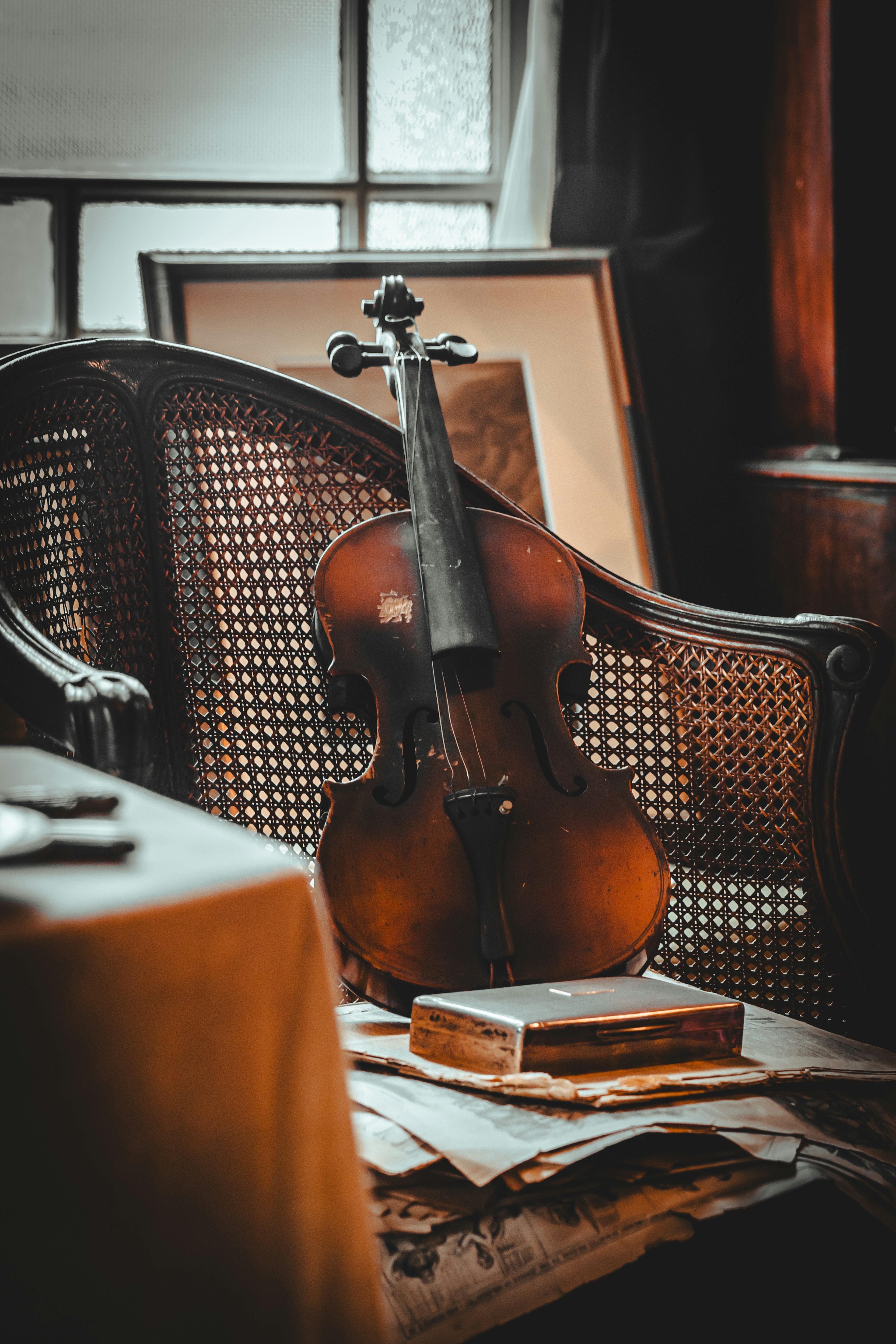 Violin resting on an antique chair with books and papers