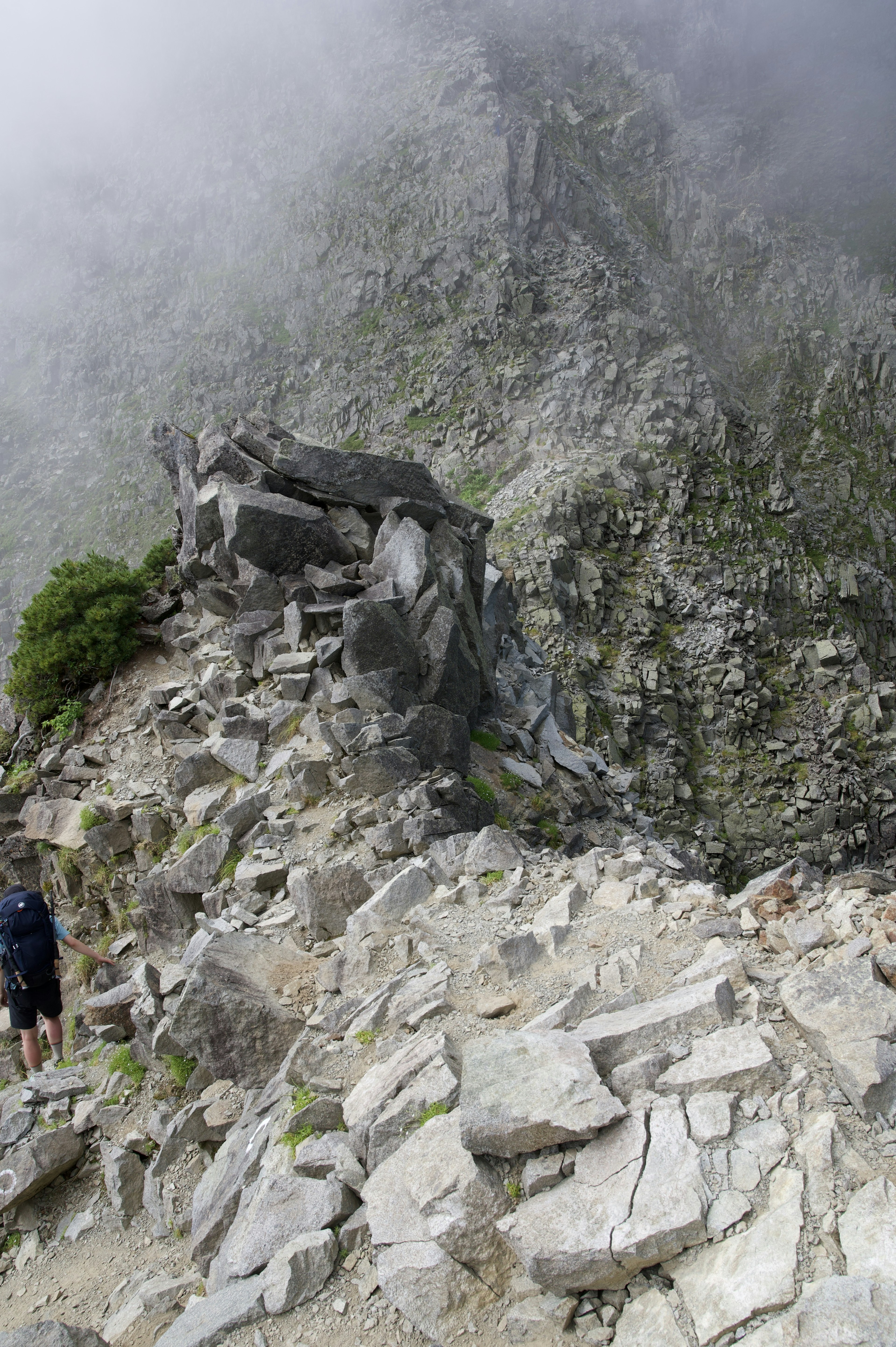 Rocky mountain trail shrouded in mist with a hiker