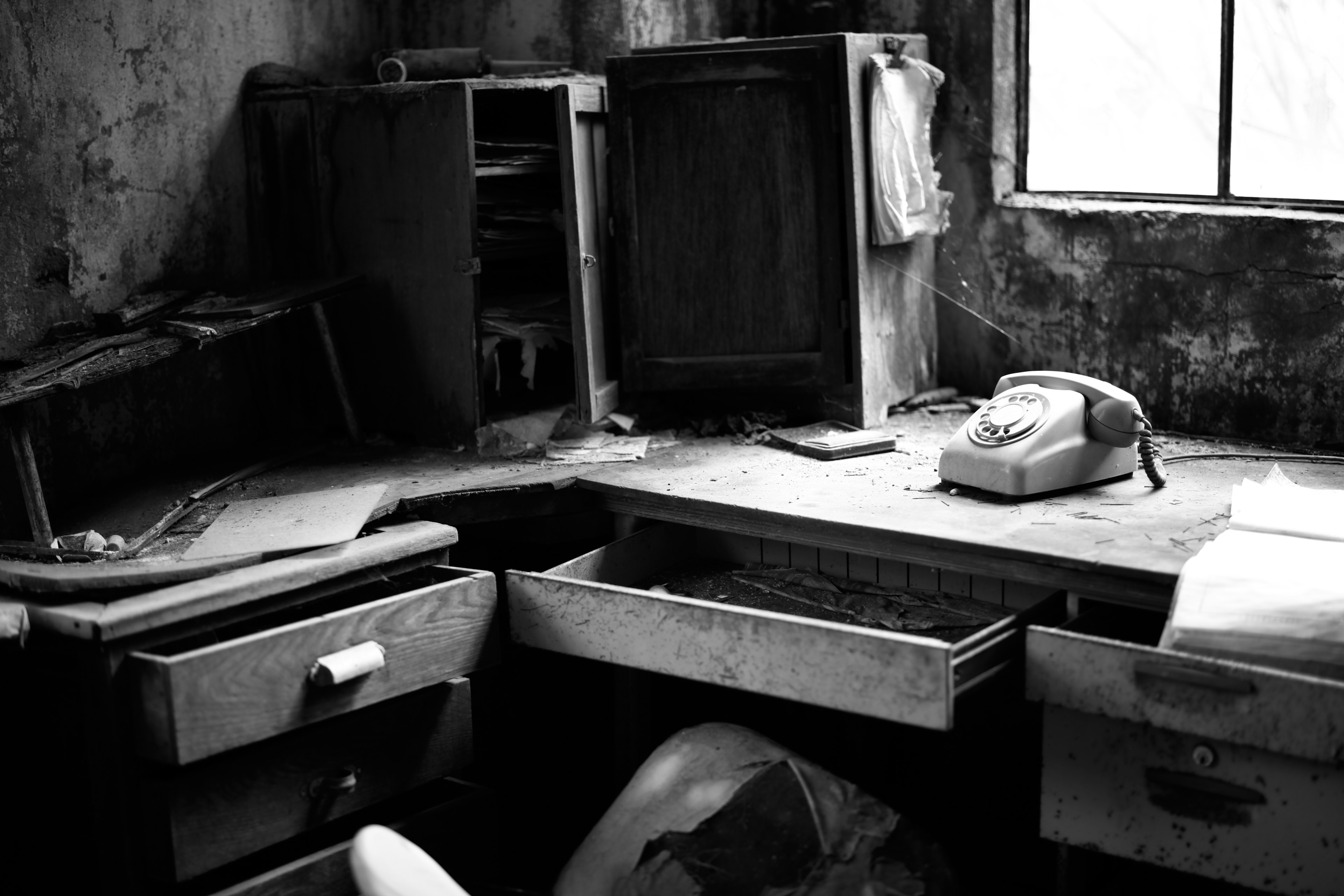 An old office desk with a telephone and open drawers in a dimly lit room