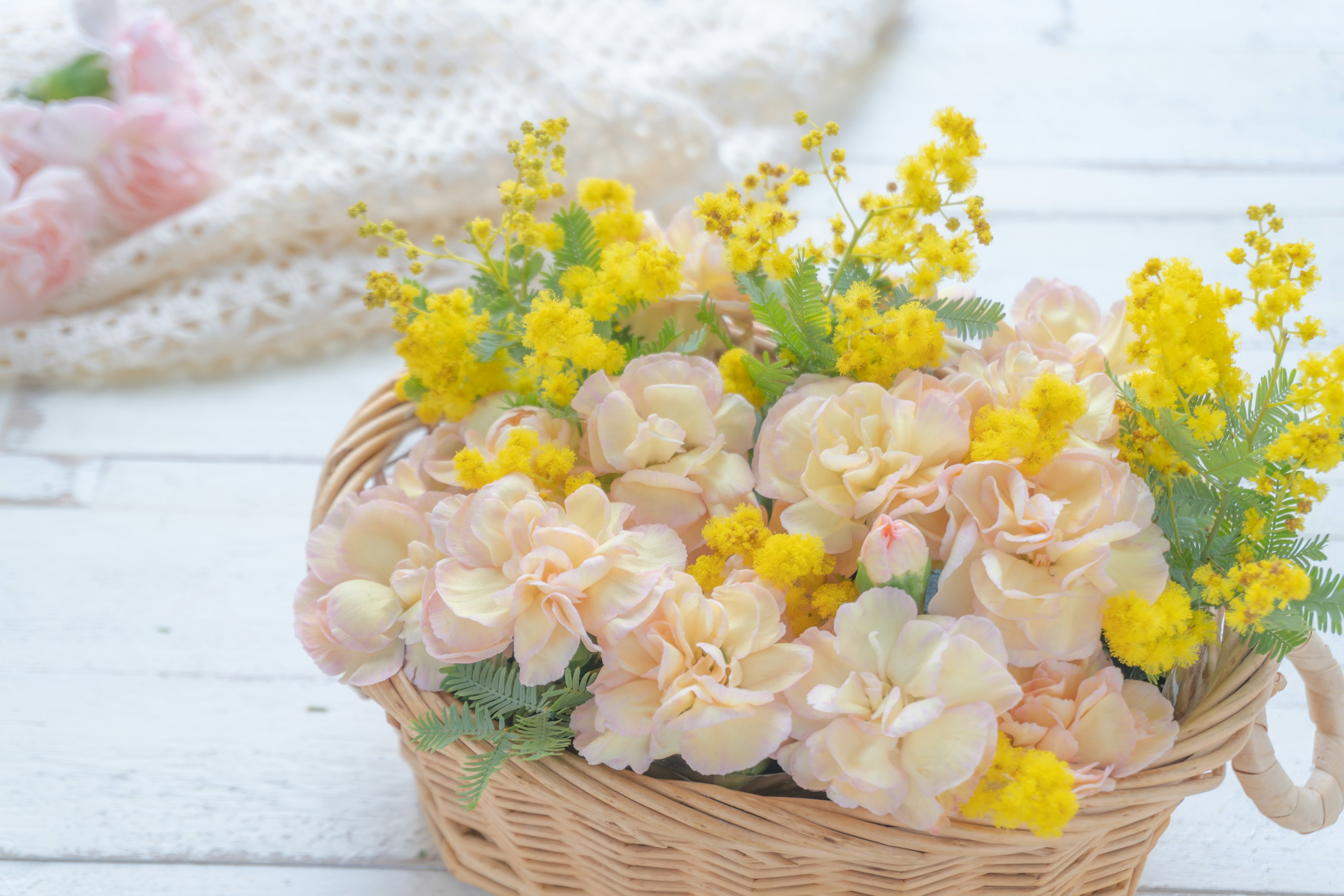 A basket filled with pink and yellow flowers arranged beautifully