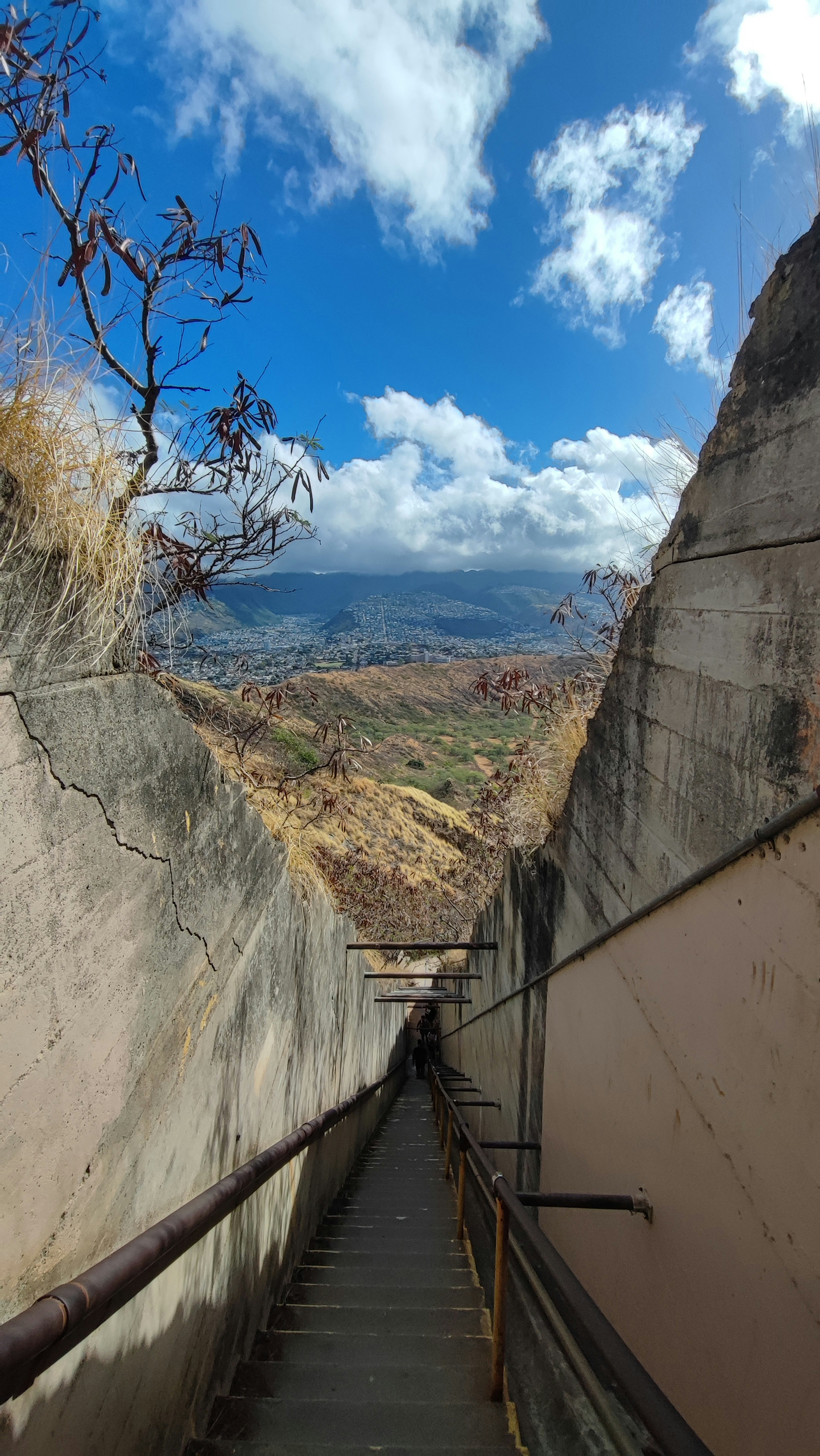 Schmale Treppe, die hinunterführt, mit Blick auf den blauen Himmel und die entfernte Landschaft