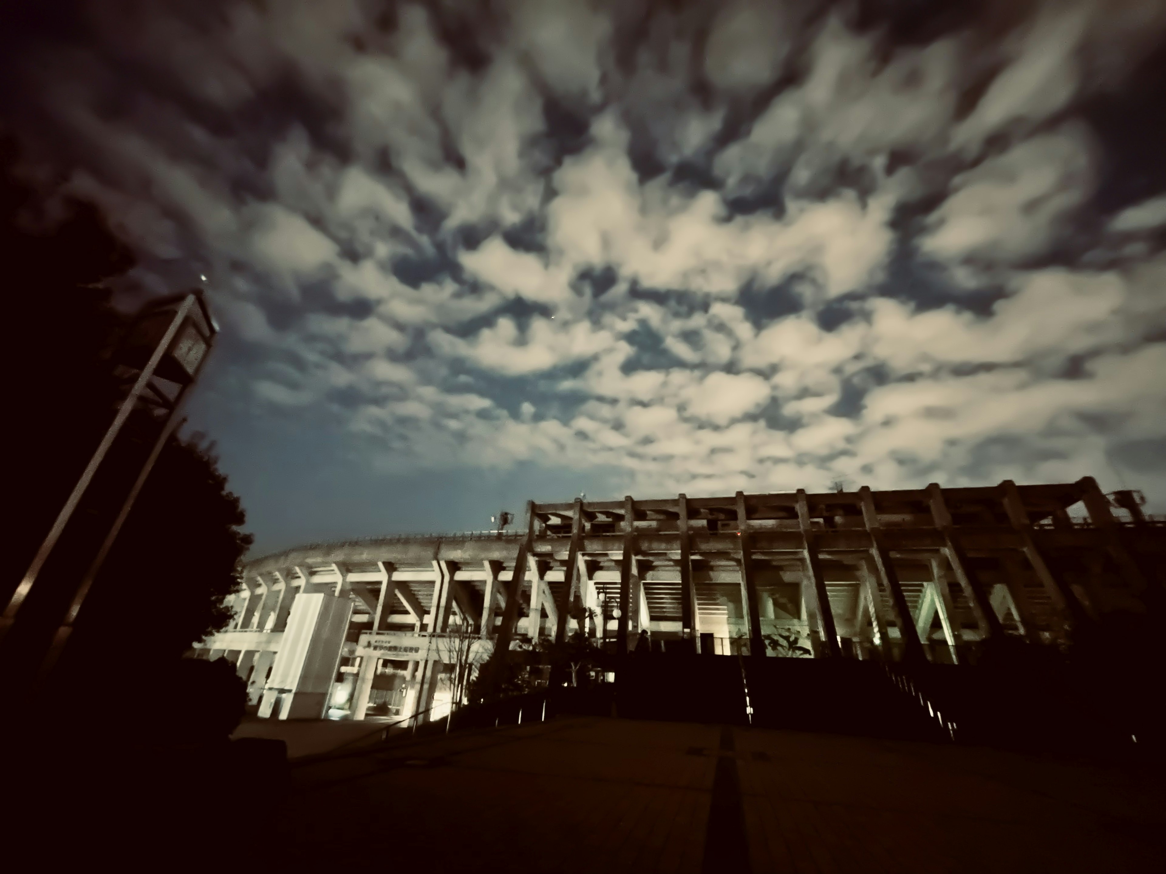 Exterior del estadio iluminado bajo un cielo nocturno nublado