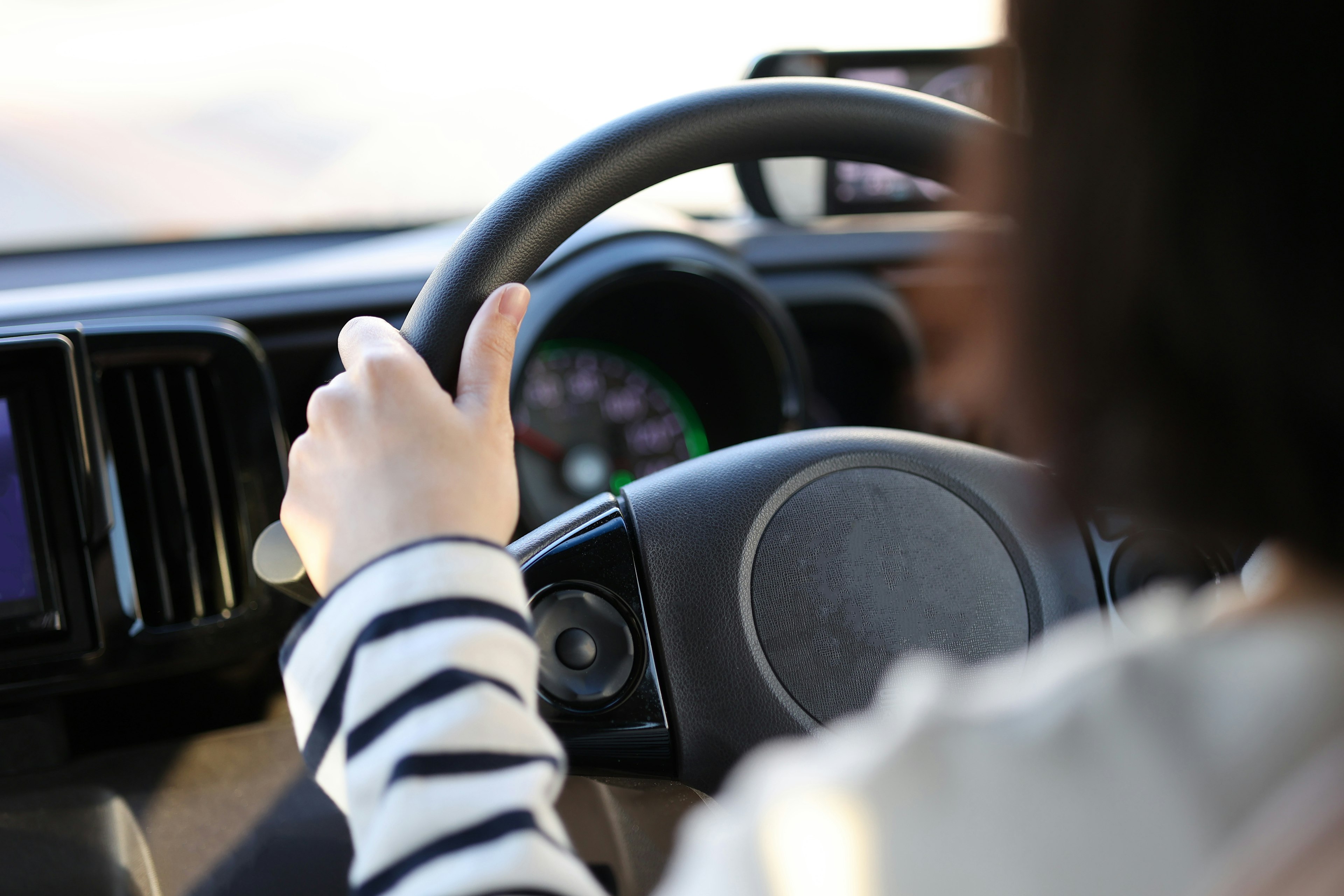 A woman's hand gripping a steering wheel while driving