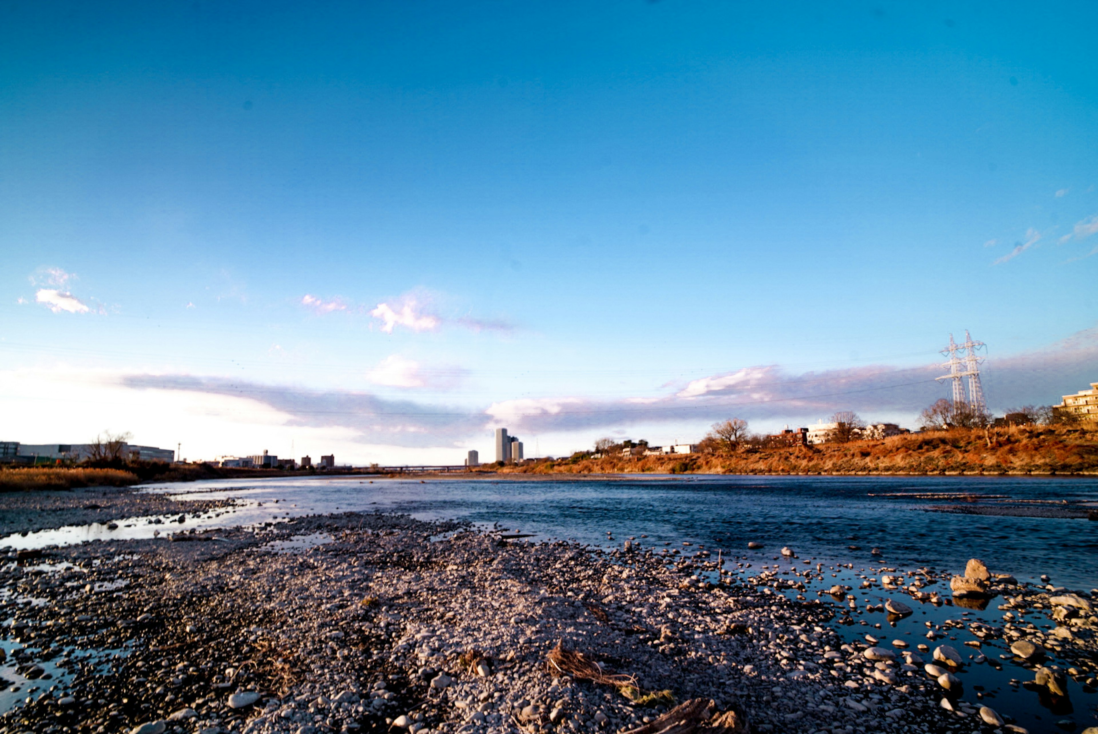 Flussuferlandschaft unter klarem blauen Himmel mit Steinen