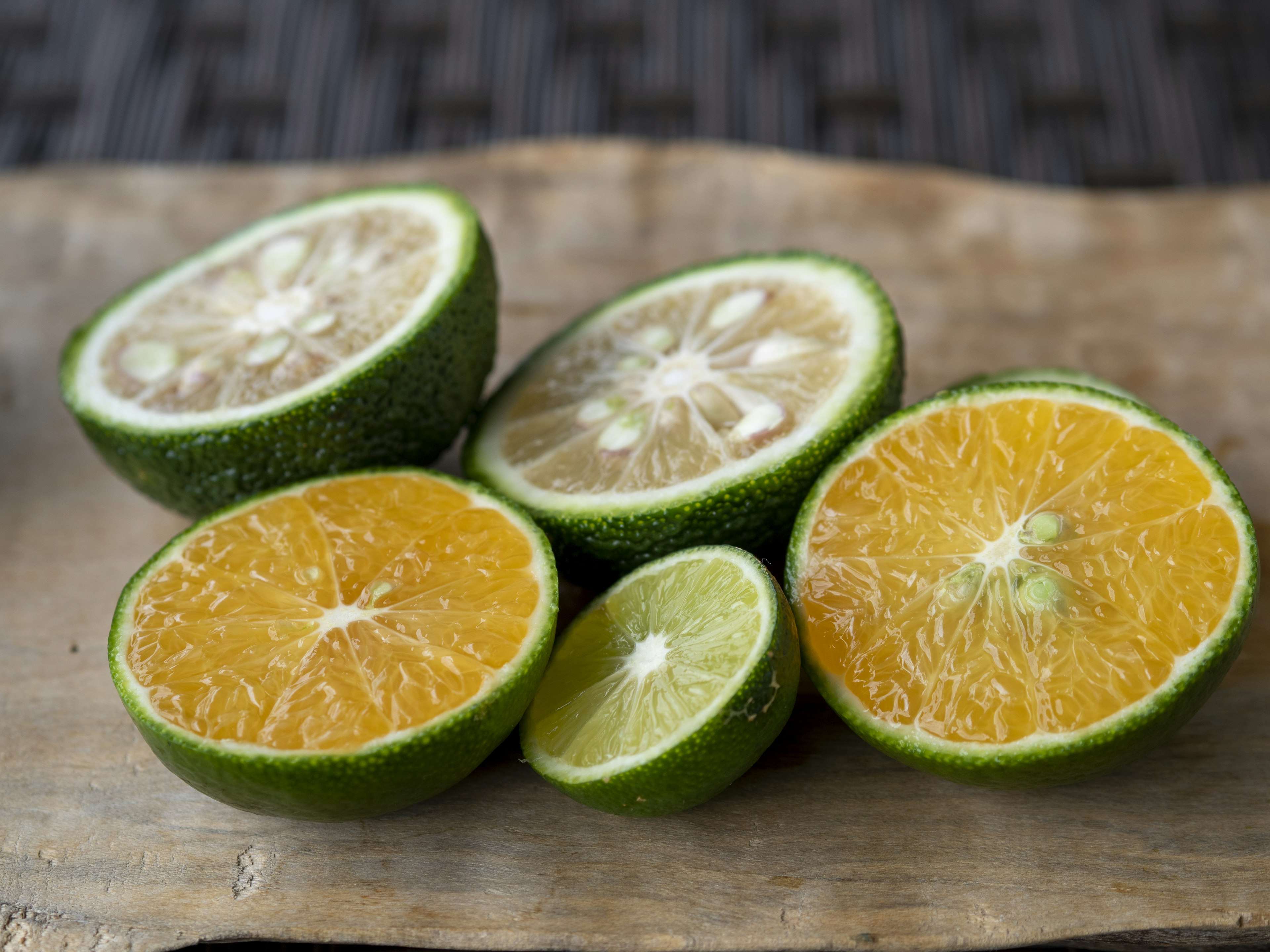 Fruits d'agrumes verts coupés en deux présentés sur une planche en bois