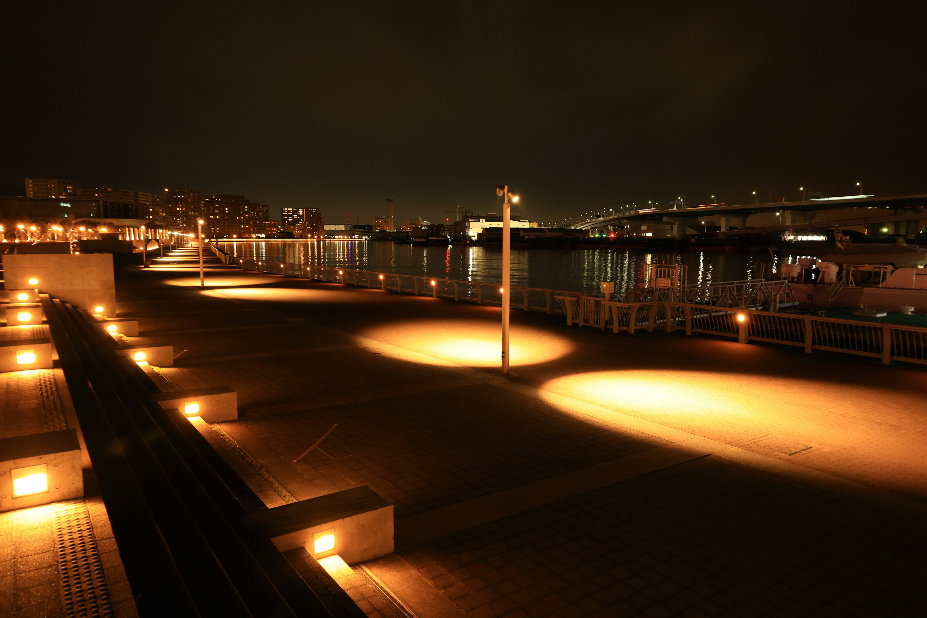 Vue nocturne d'un port avec des chemins éclairés se reflétant sur l'eau