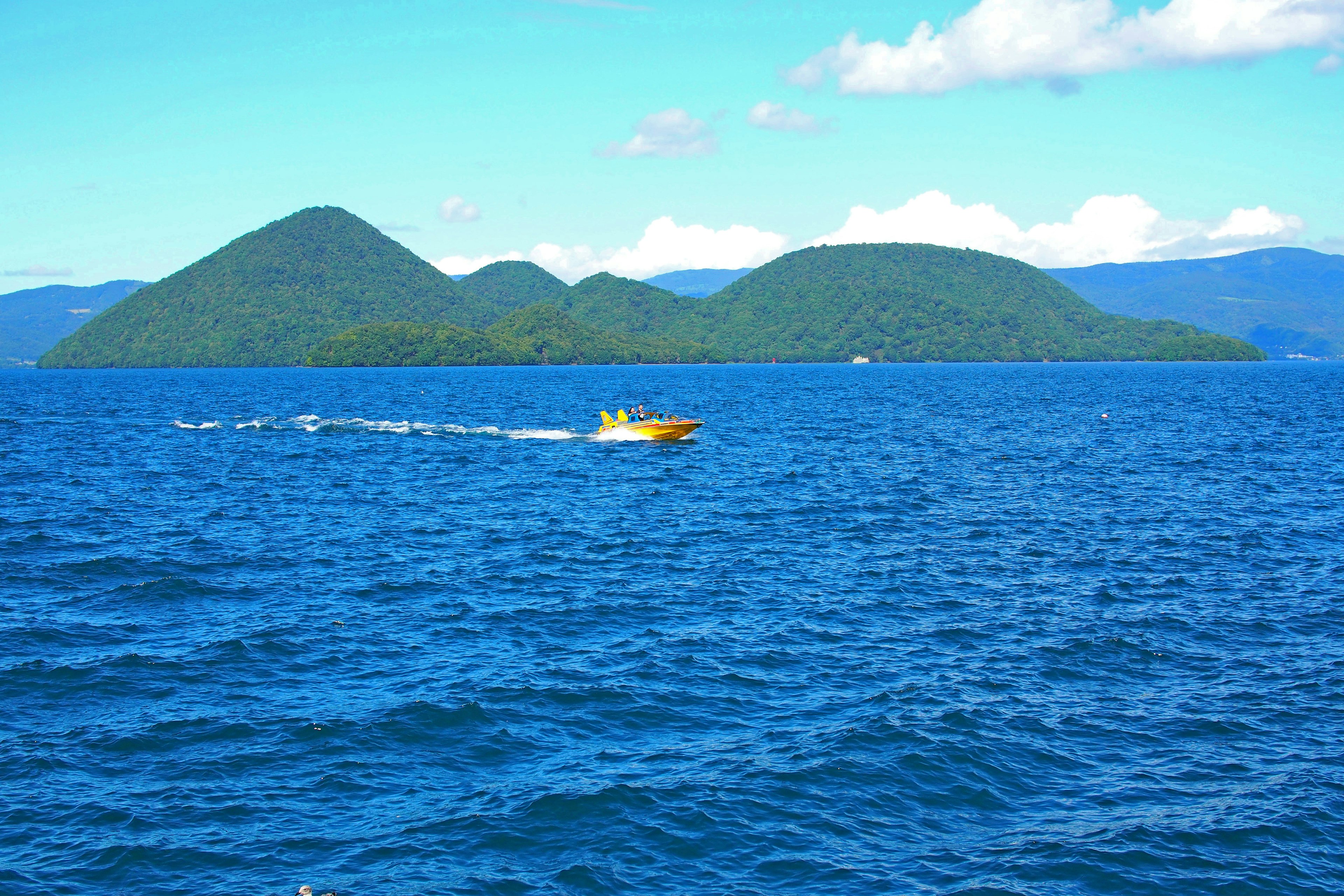 Green islands floating in blue sea with a boat