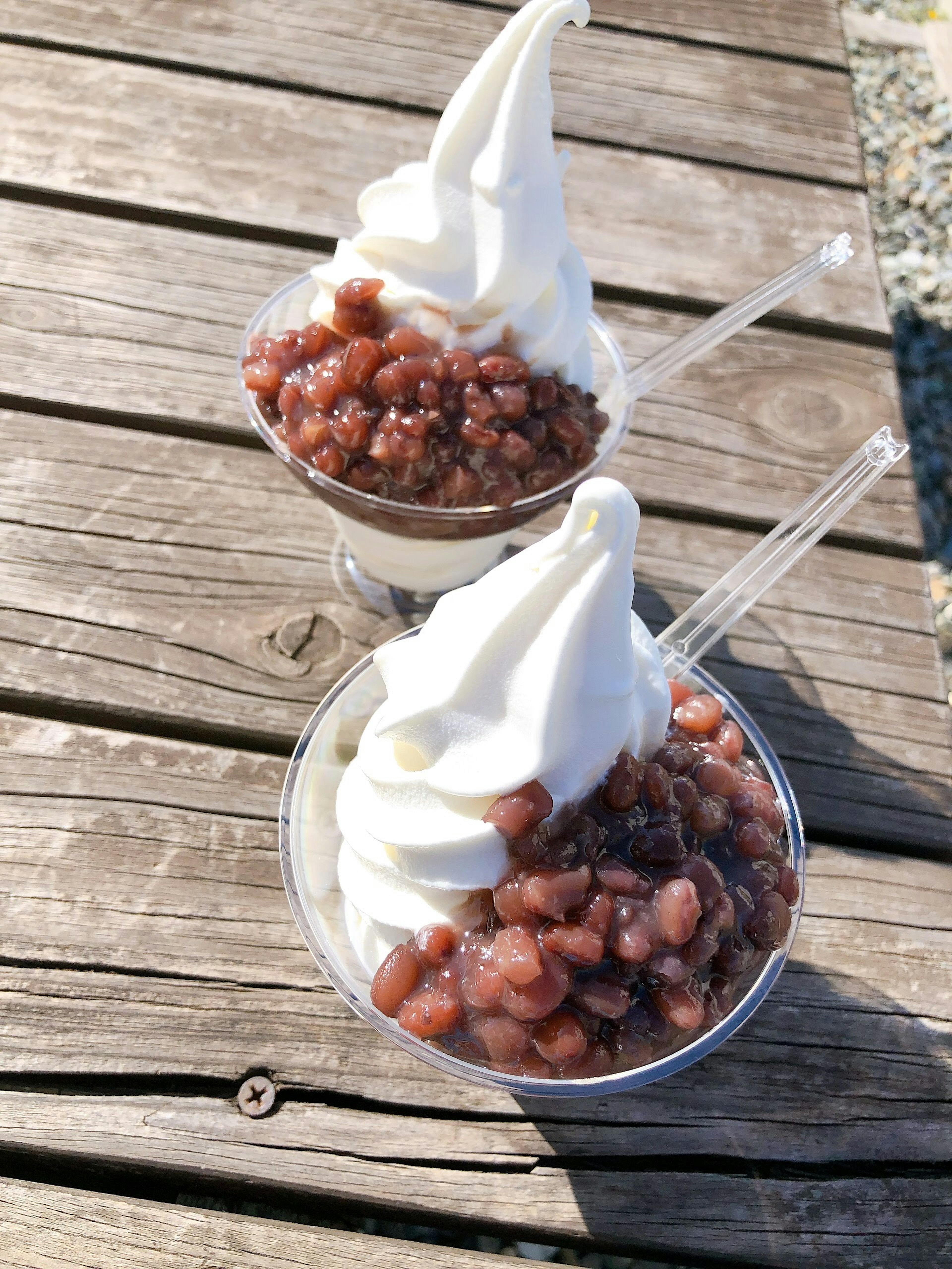 Dos copas de helado cubiertas con crema blanca y frijoles rojos