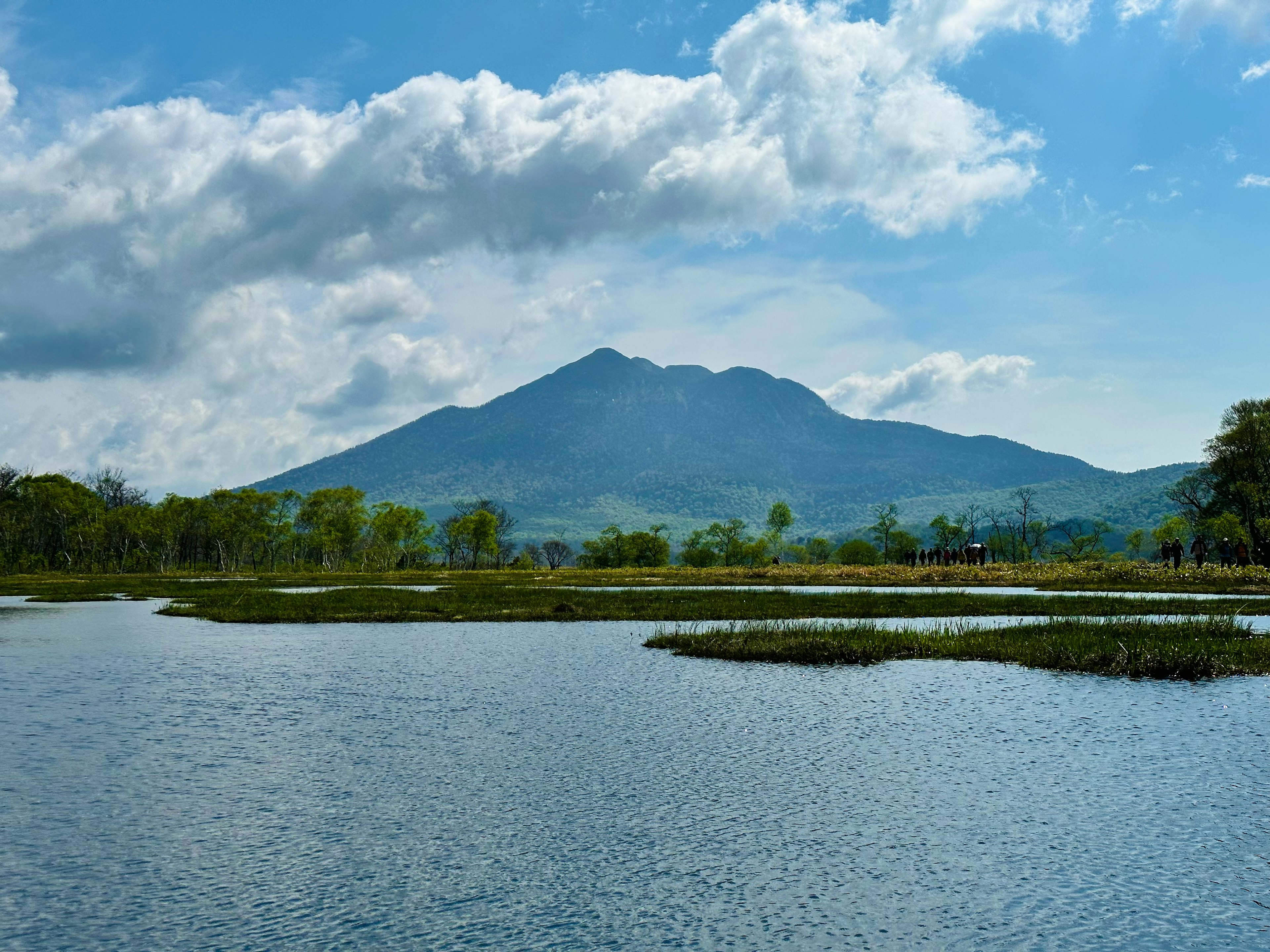 青い空と白い雲の下に広がる水面と山の風景