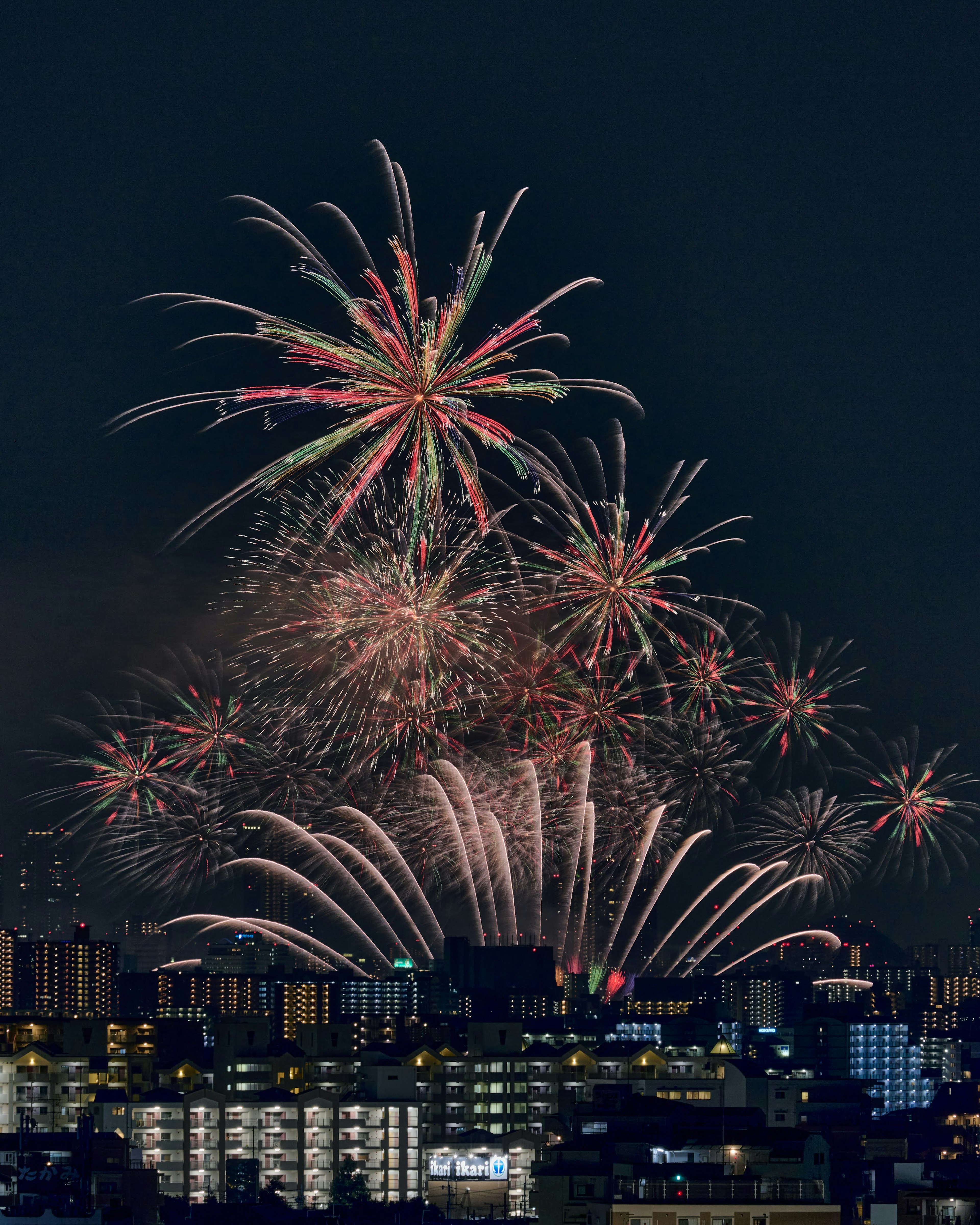 Vibrant fireworks display in the night sky with a city skyline in the background