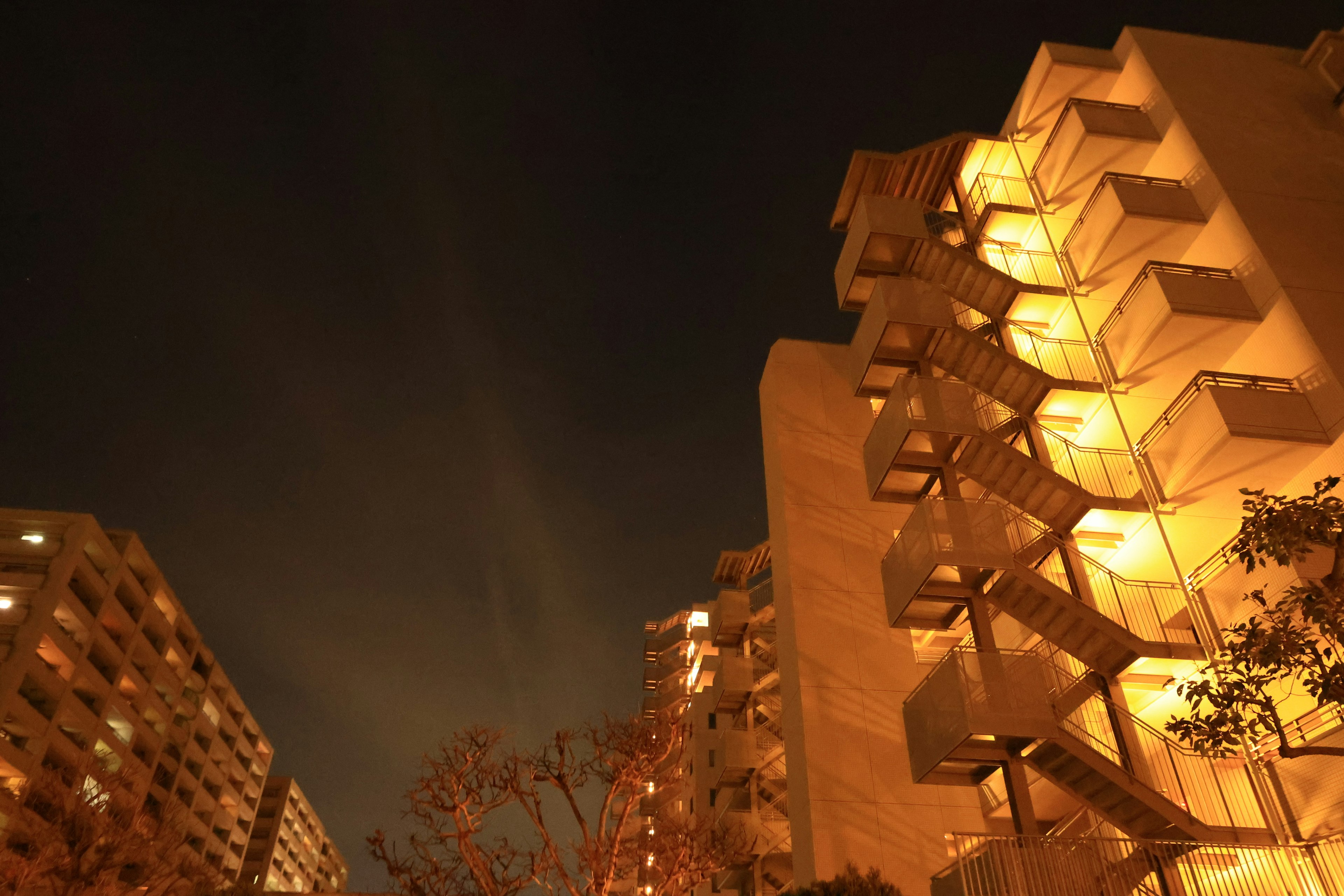 Vista nocturna de apartamentos altos con escaleras iluminadas