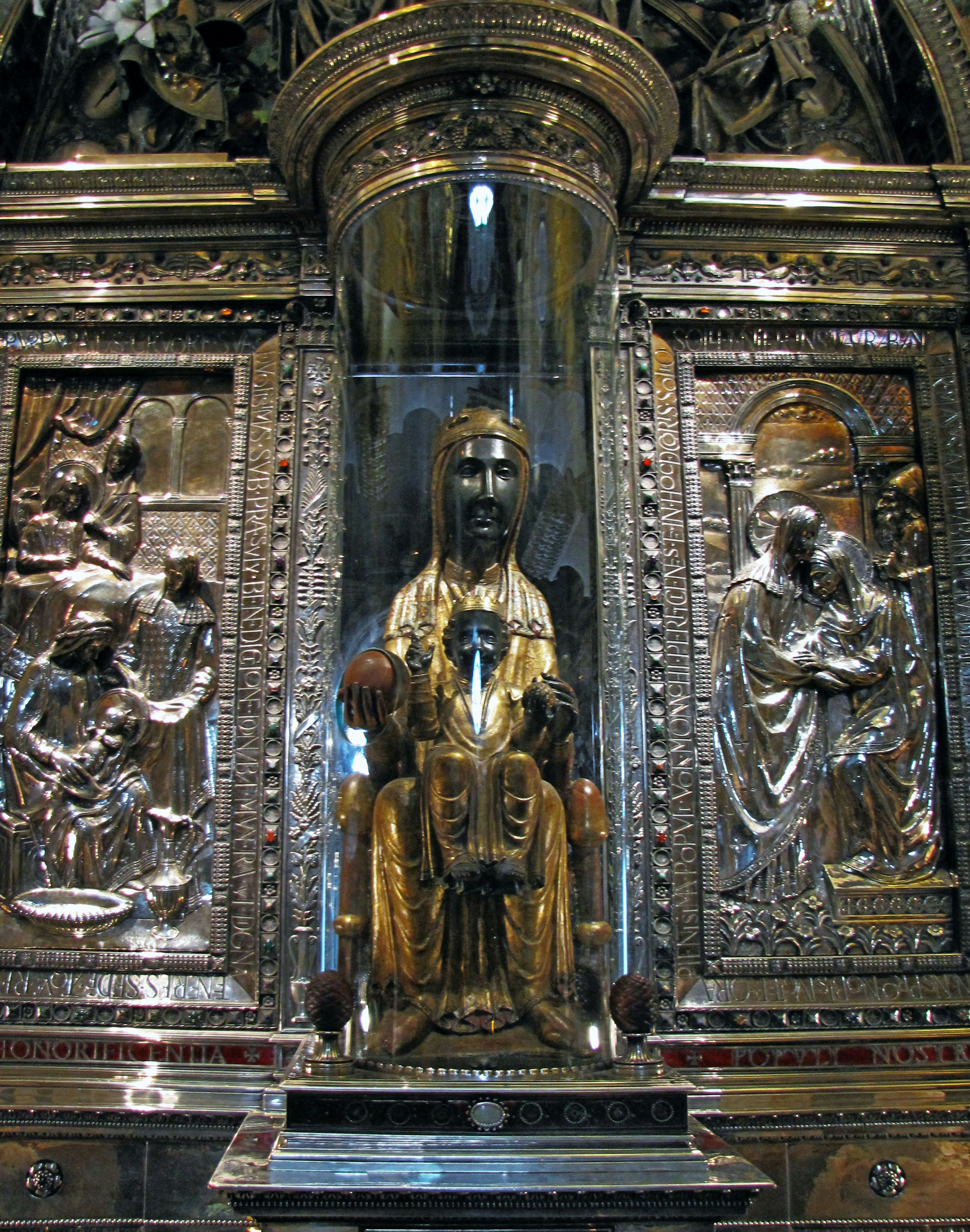 Golden statue of the Virgin Mary inside a glass case surrounded by intricate carvings